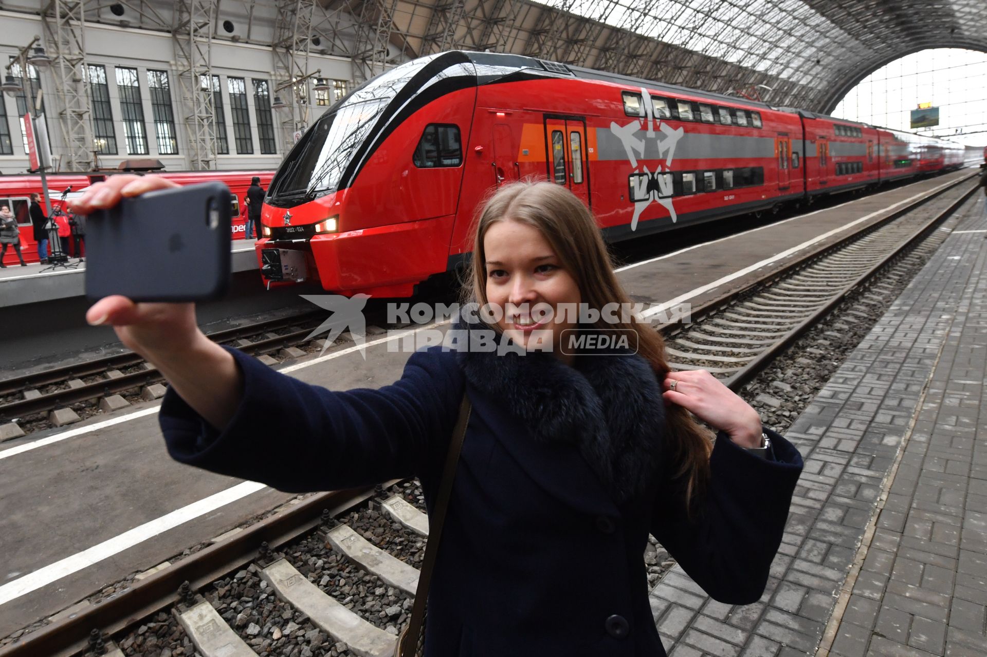 Москва.  Девушка делает селфи на фоне двухэтажного   аэроэкспресса, произведенного  в Беларуси , на перроне Киевского вокзала.