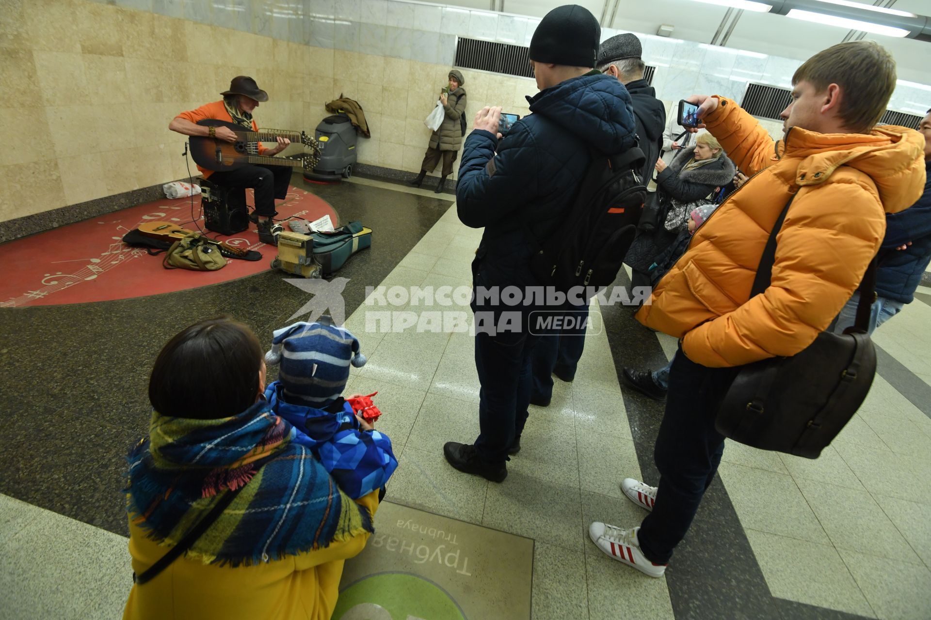 Москва.  Прохожие слушают игру музыканта в метро.