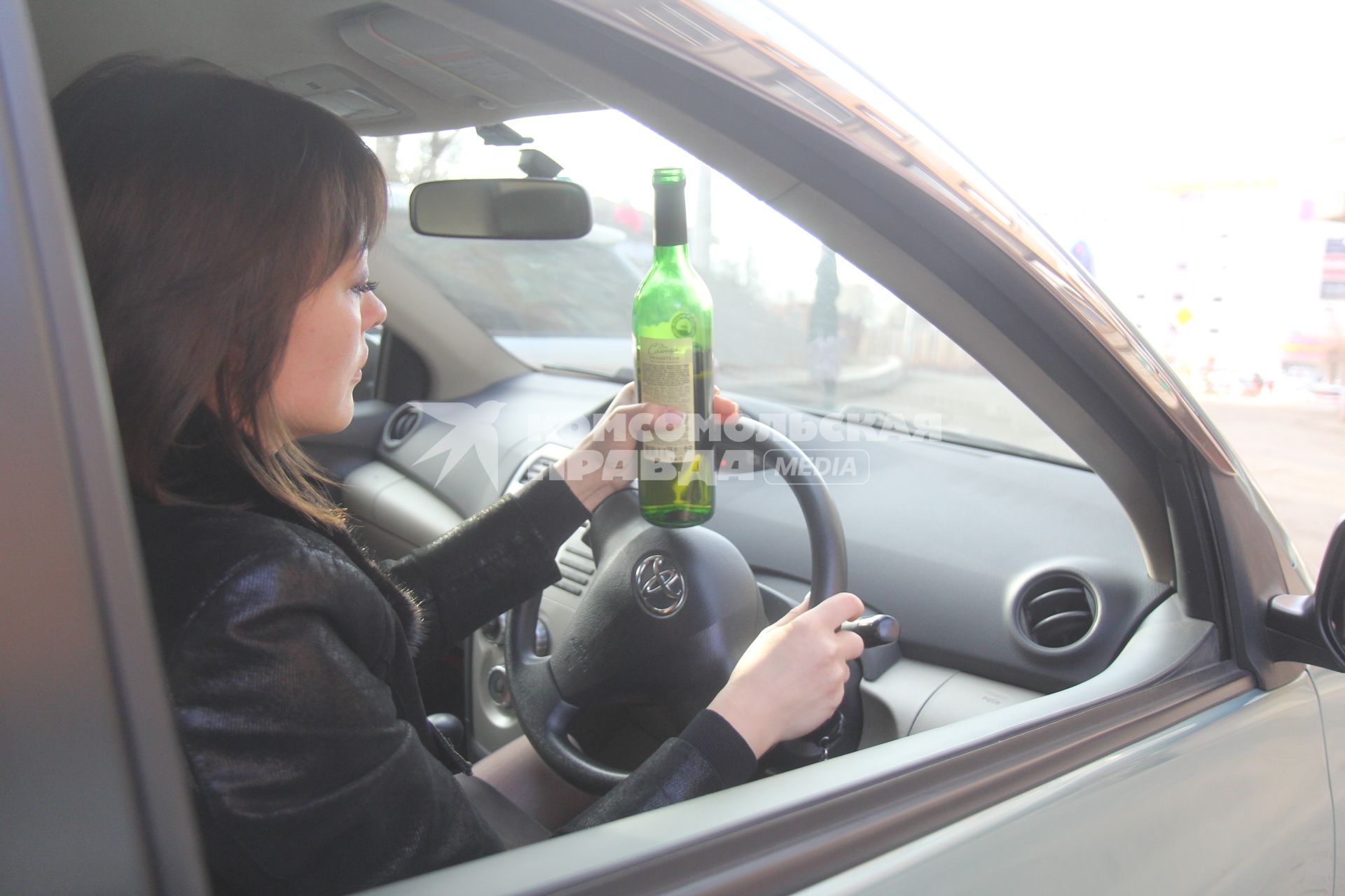 Иркутск. Девушка за рулем автомобиля пьет вино.