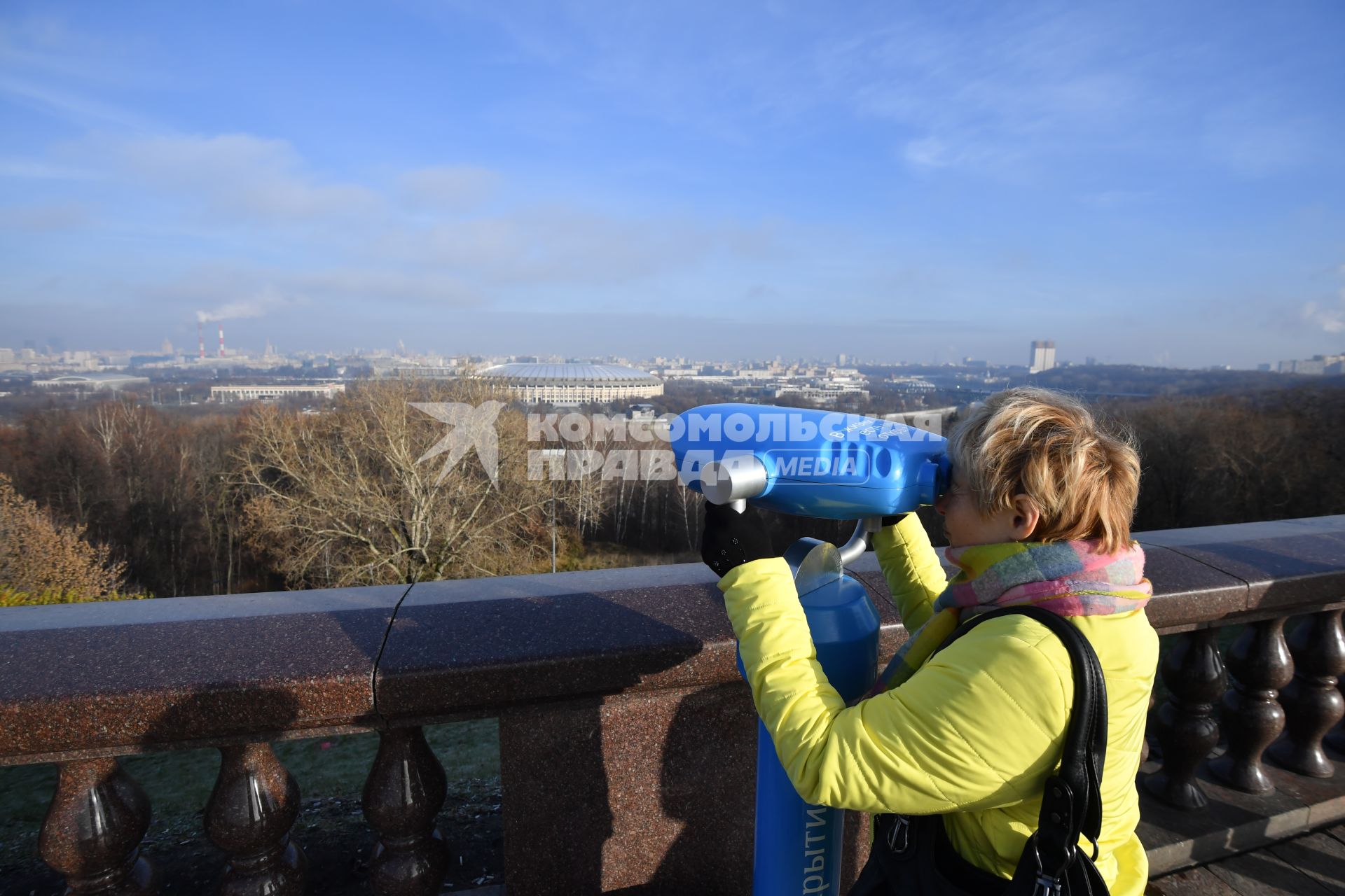 Москва.  Женщина смотрит в бинокль на смотровой площадке Воробьевых гор.