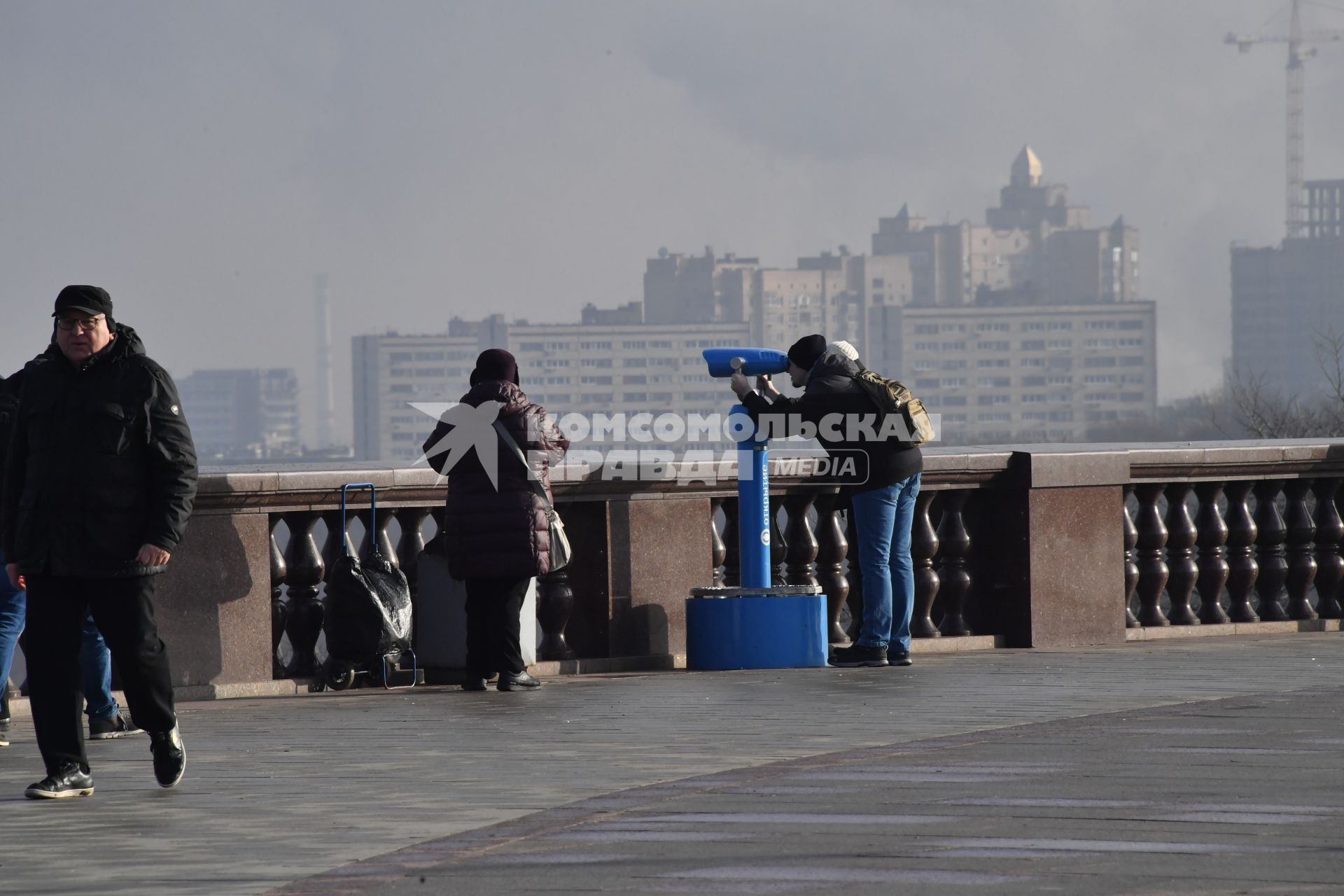 Москва.  Мужчина смотрит в бинокль на смотровой площадке Воробьевых гор.