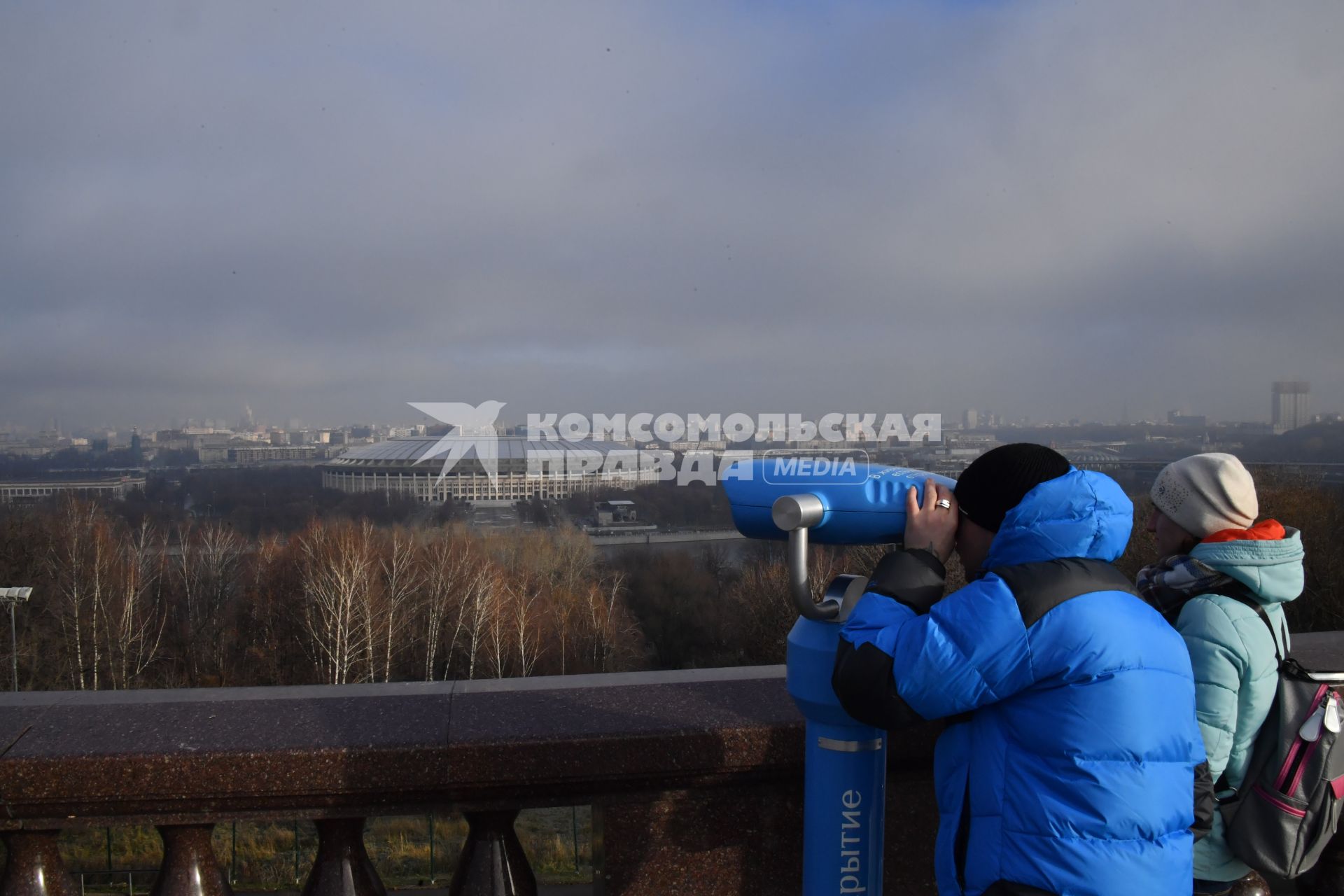 Москва.  Мужчина смотрит в бинокль на смотровой площадке Воробьевых гор.