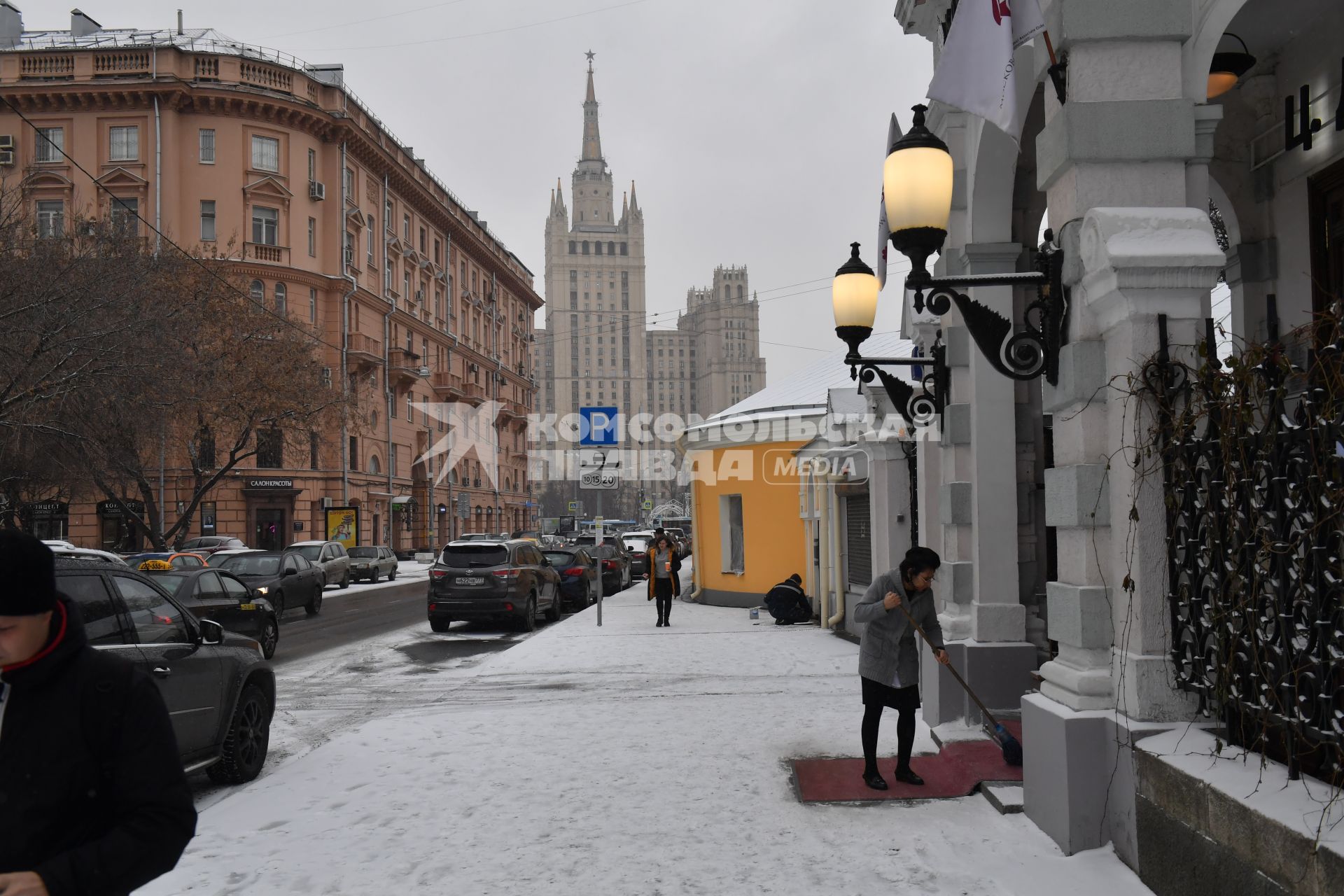 Москва.  Служащая чистит ковровую дорожку  у посольства на Поварской улице. на Поварской улице.