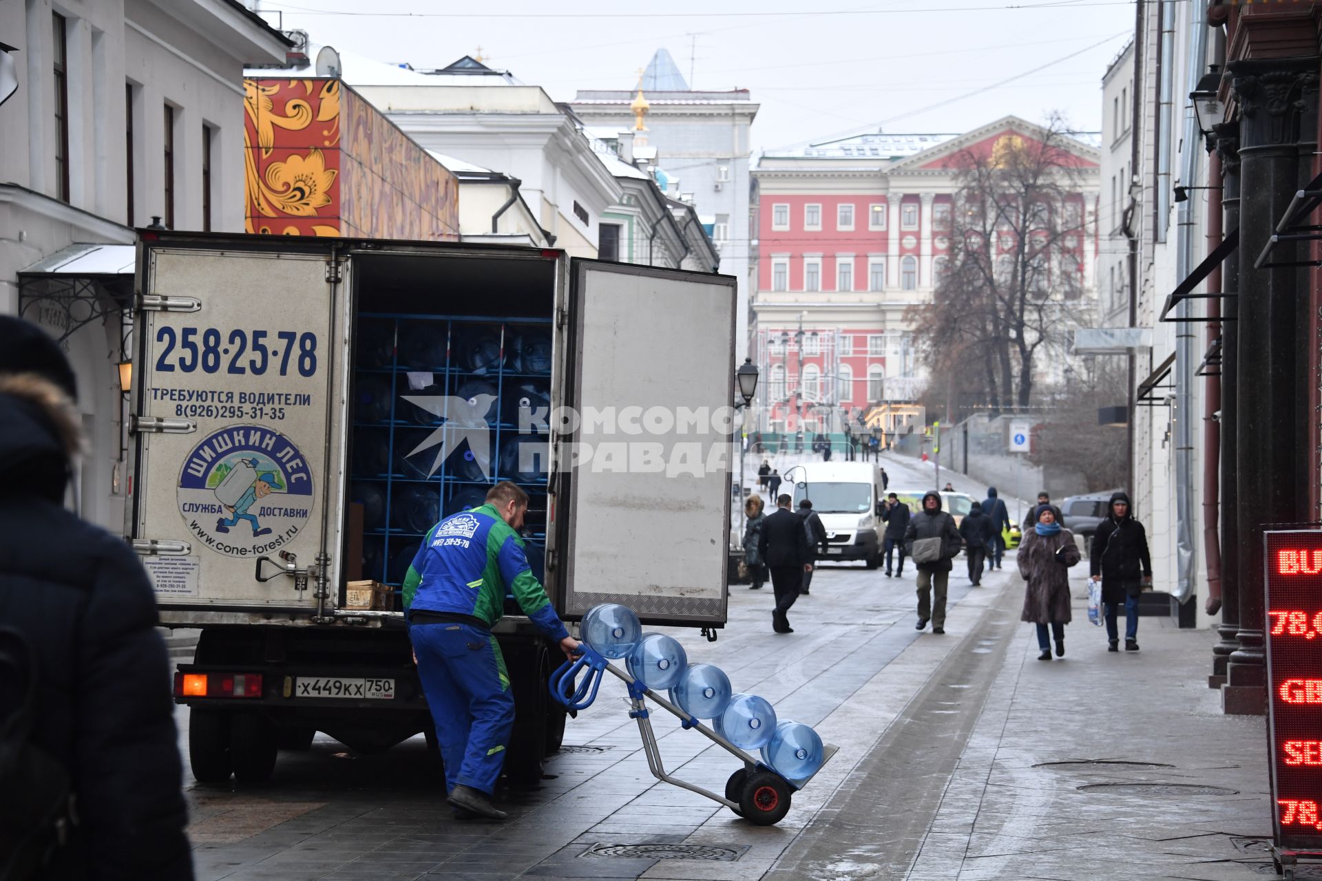 Москва.  Рабочий грузит бутыли из-под воды в грузовую машину в Столешниковом переулке.