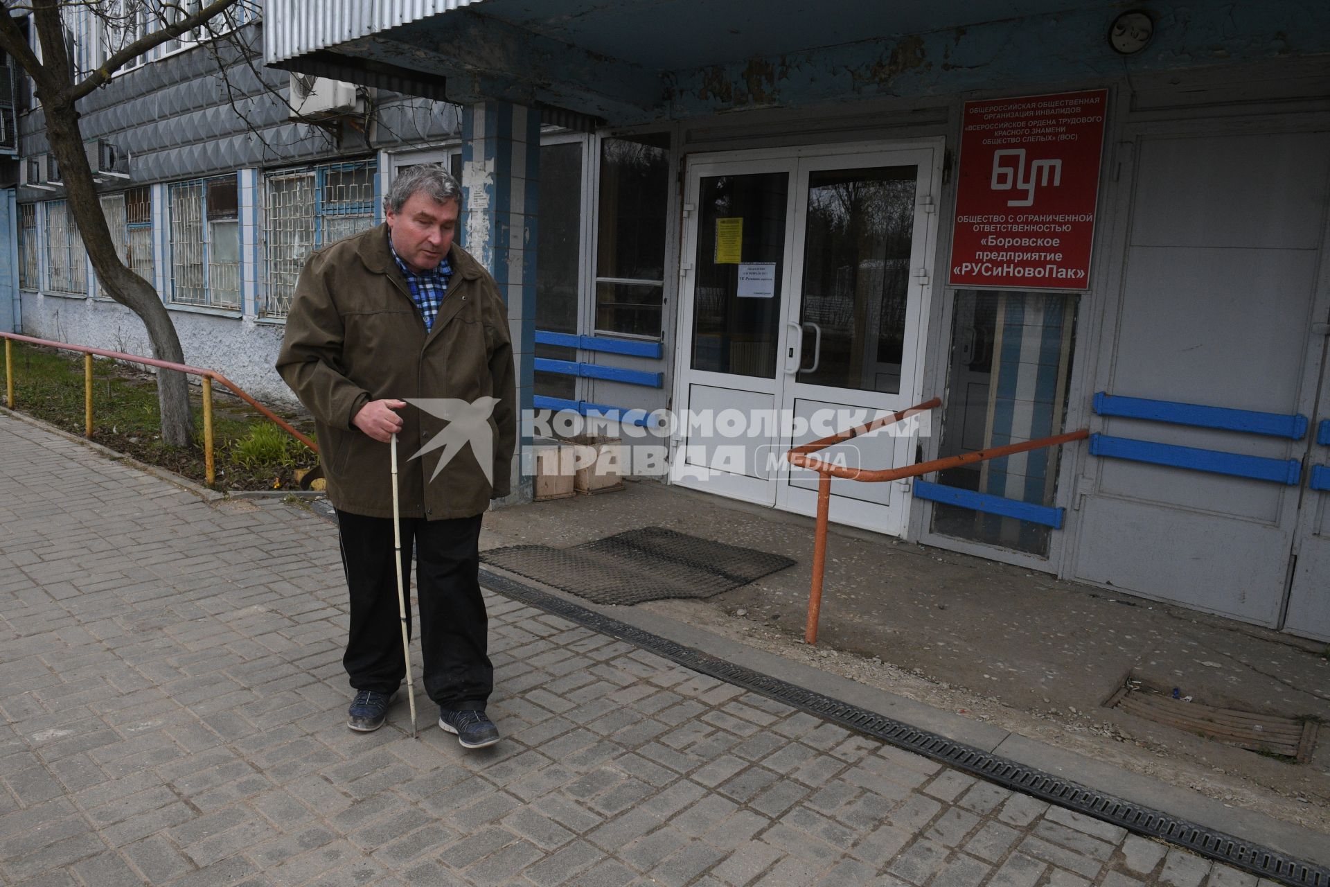 Русиново.  Мужчина у входа на Боровское предприятие `Рус и Ново Пак`  Всероссийского общества слепых.