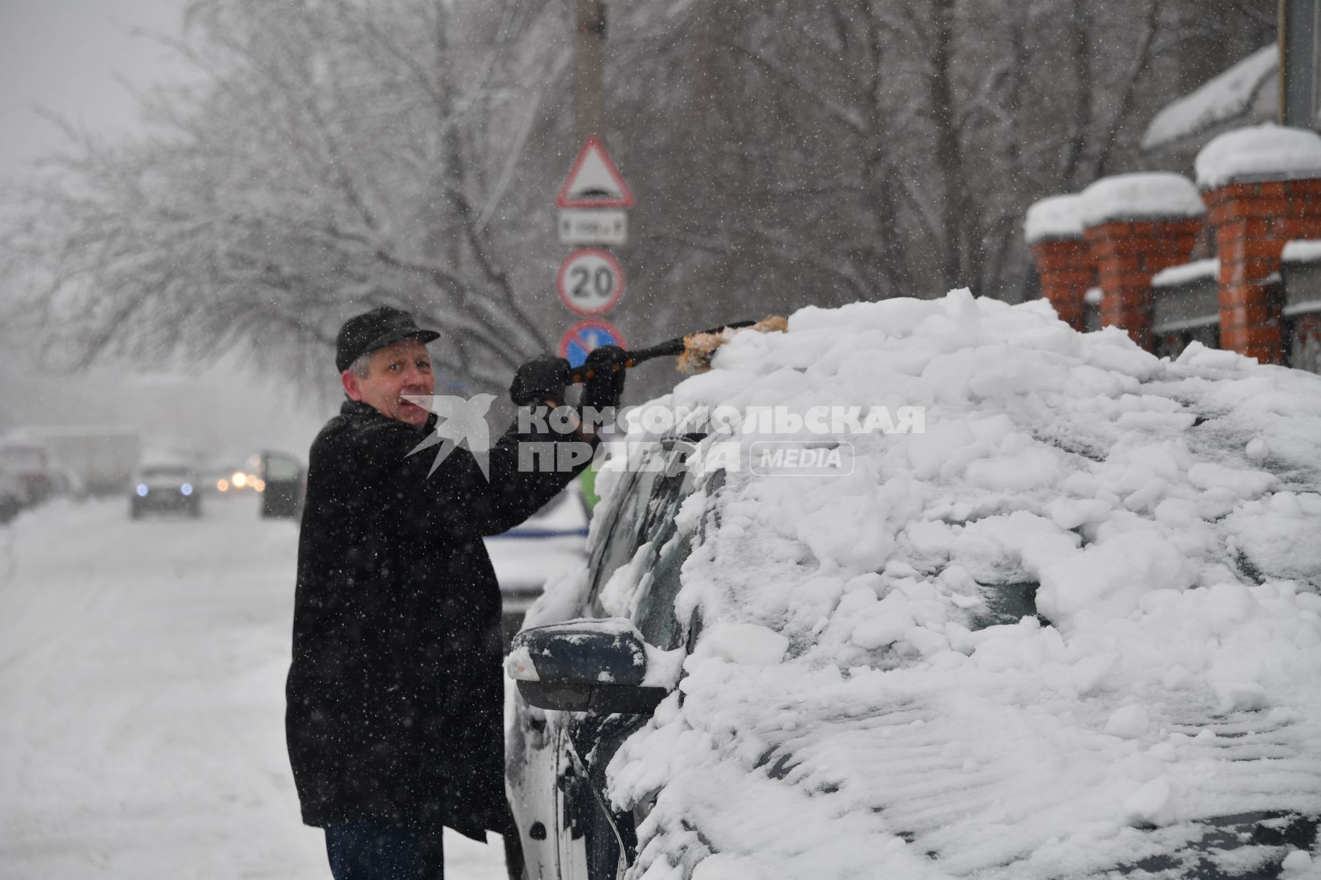 Москва. Мужчина очищает  машину от снега