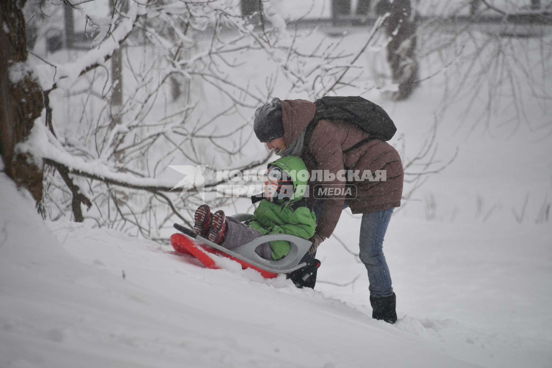 Москва. Женщина везет ребенка на санках.