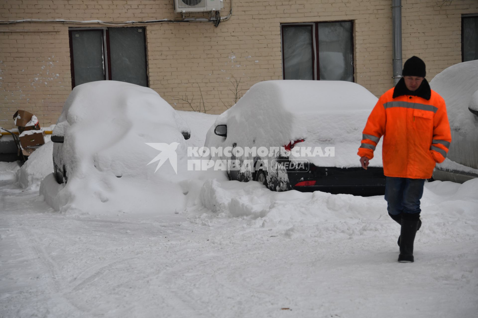 Москва . Дворник идет мимо занесенных снегом машин.