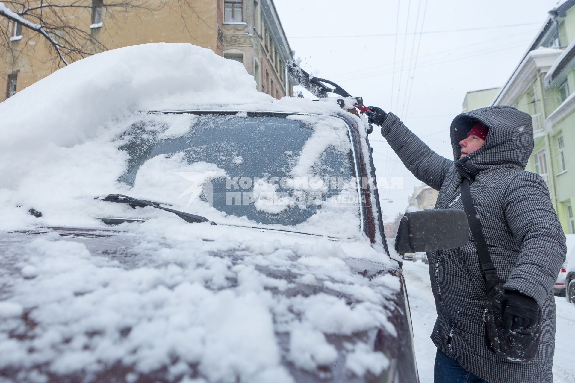 Санкт-Петербург.  Мужчина очищает машину от снега.
