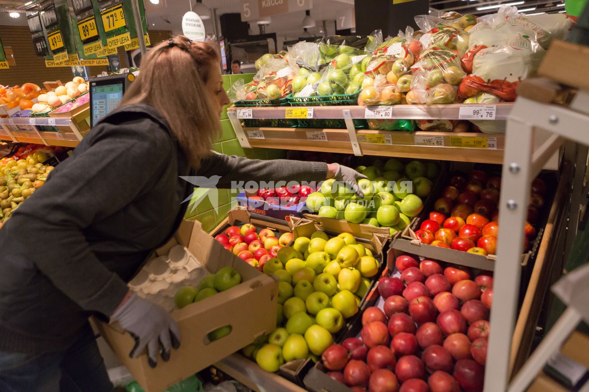 Санкт-Петербург.   Сотрудница выкладывает яблоки на прилавок  в супермаркете `Перекресток`.