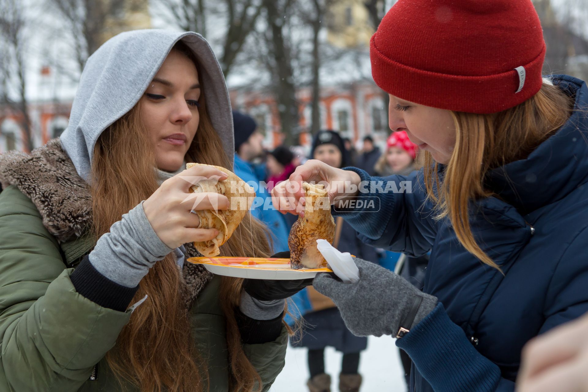 Санкт-Петербург. Девушки  едят  блины   во время празднования  `Широкой Масленицы`  в Петропавловской крепости.