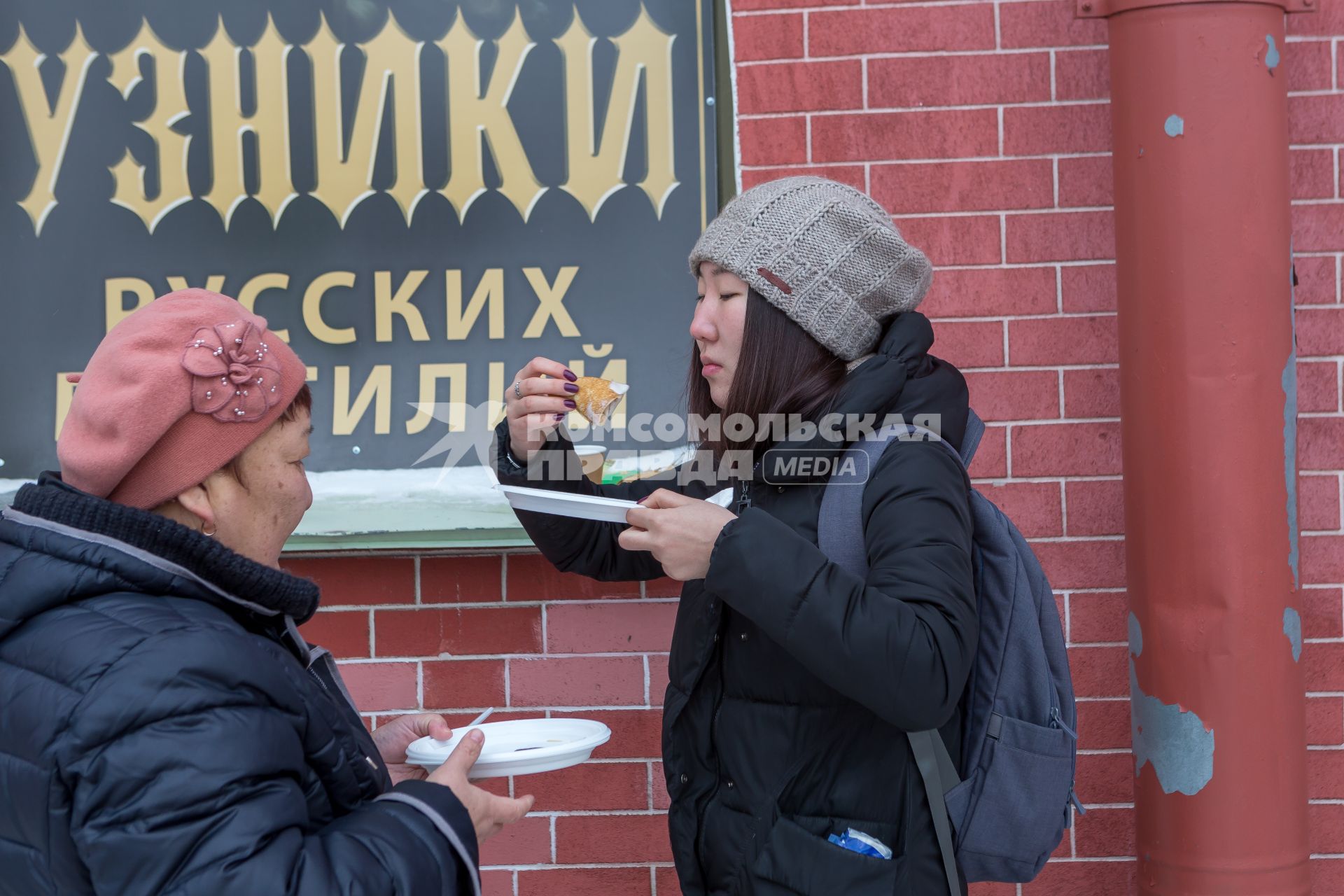 Санкт-Петербург.  Китайские туристки едят блины во время празднования  `Широкой Масленицы`  в Петропавловской крепости.