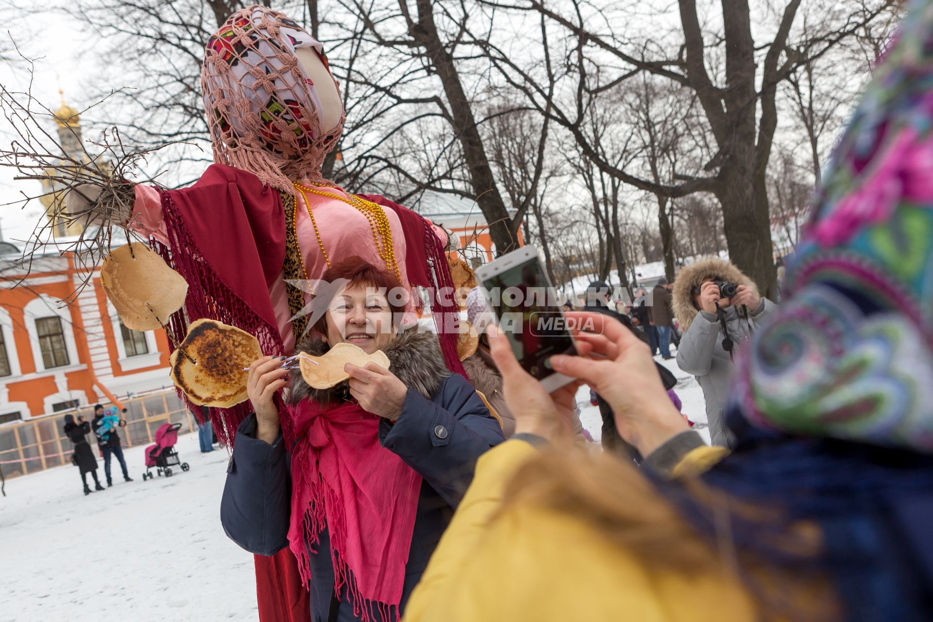 Санкт-Петербург.  Женщина фотографируется у чучела  во время празднования  `Широкой Масленицы`  в Петропавловской крепости.