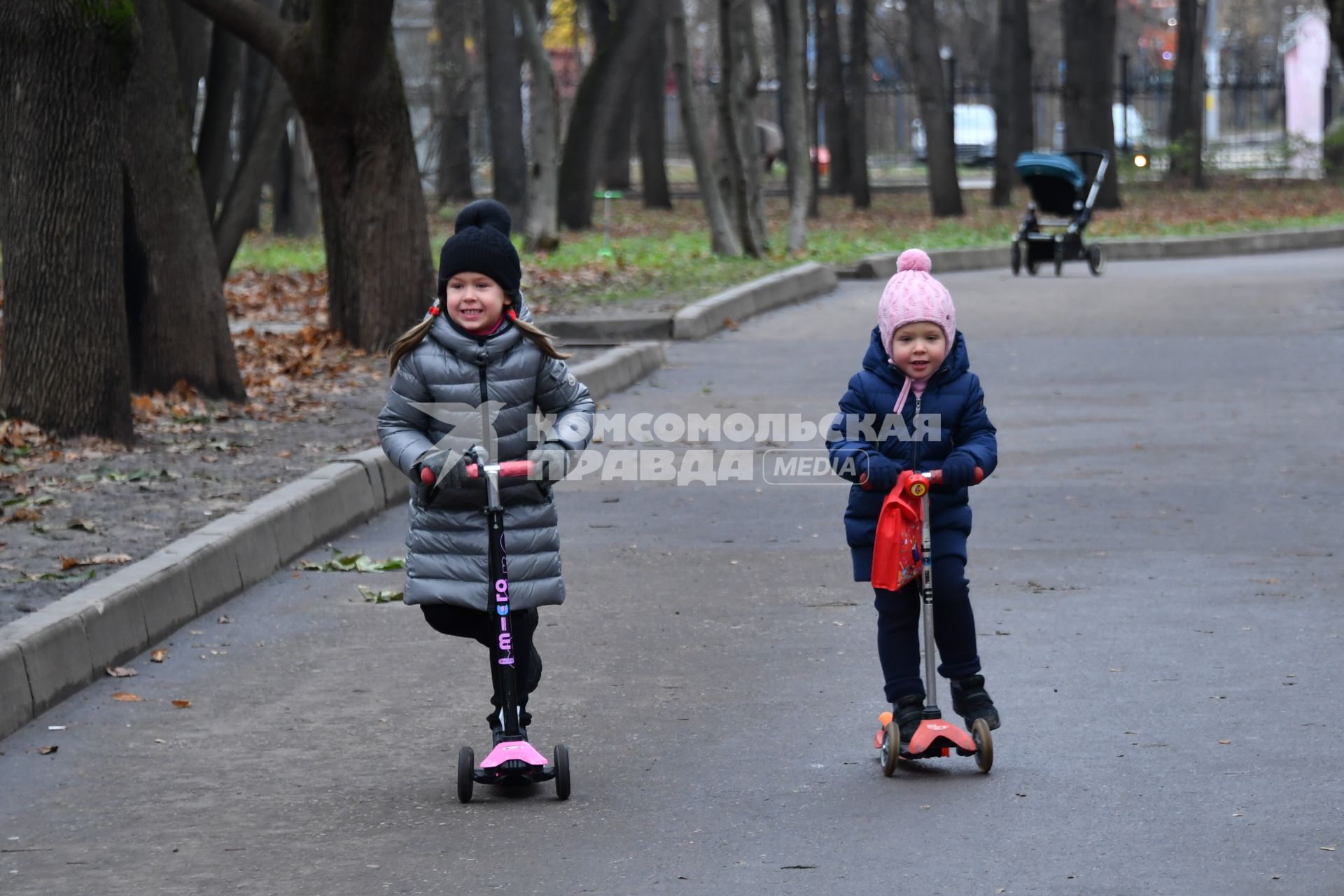 Москва.  Девочки катаются на самокатах в парке