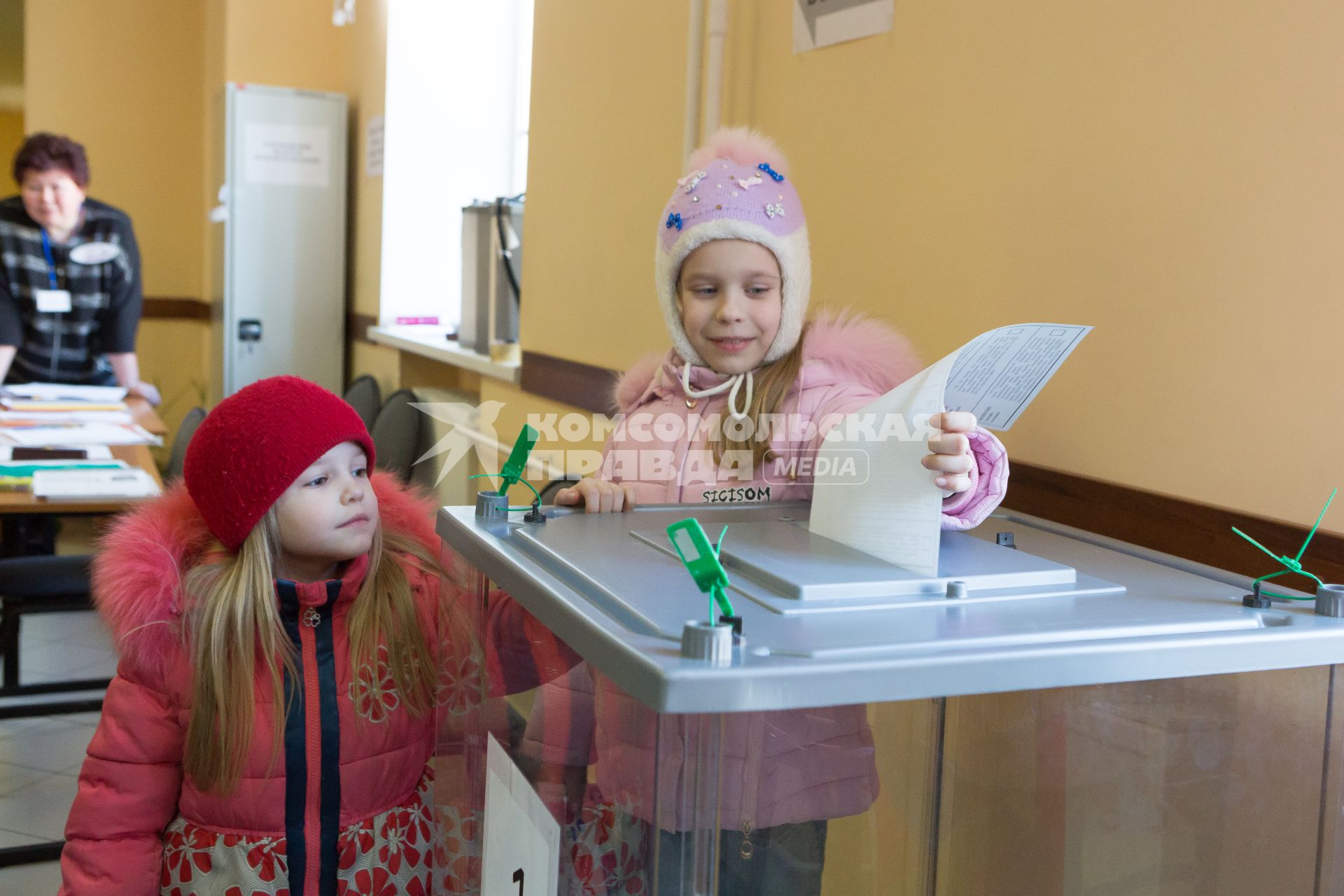 Санкт-Петербург.  Девочка опускает бюллетень  в урну  для голосования  во время выборов президента России.