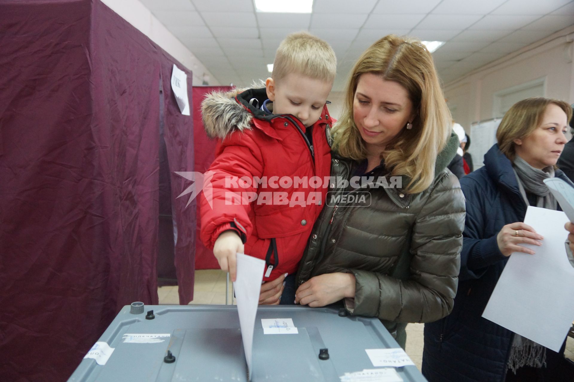 Самара. Женщина с ребенком во время голосования на выборах президента РФ на избирательном участке #3011.