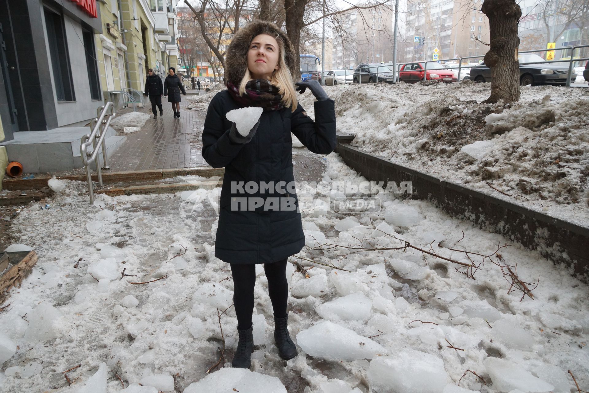 Самара. Девушка держит в руках  кусок льда, который счищали с крыши дома .