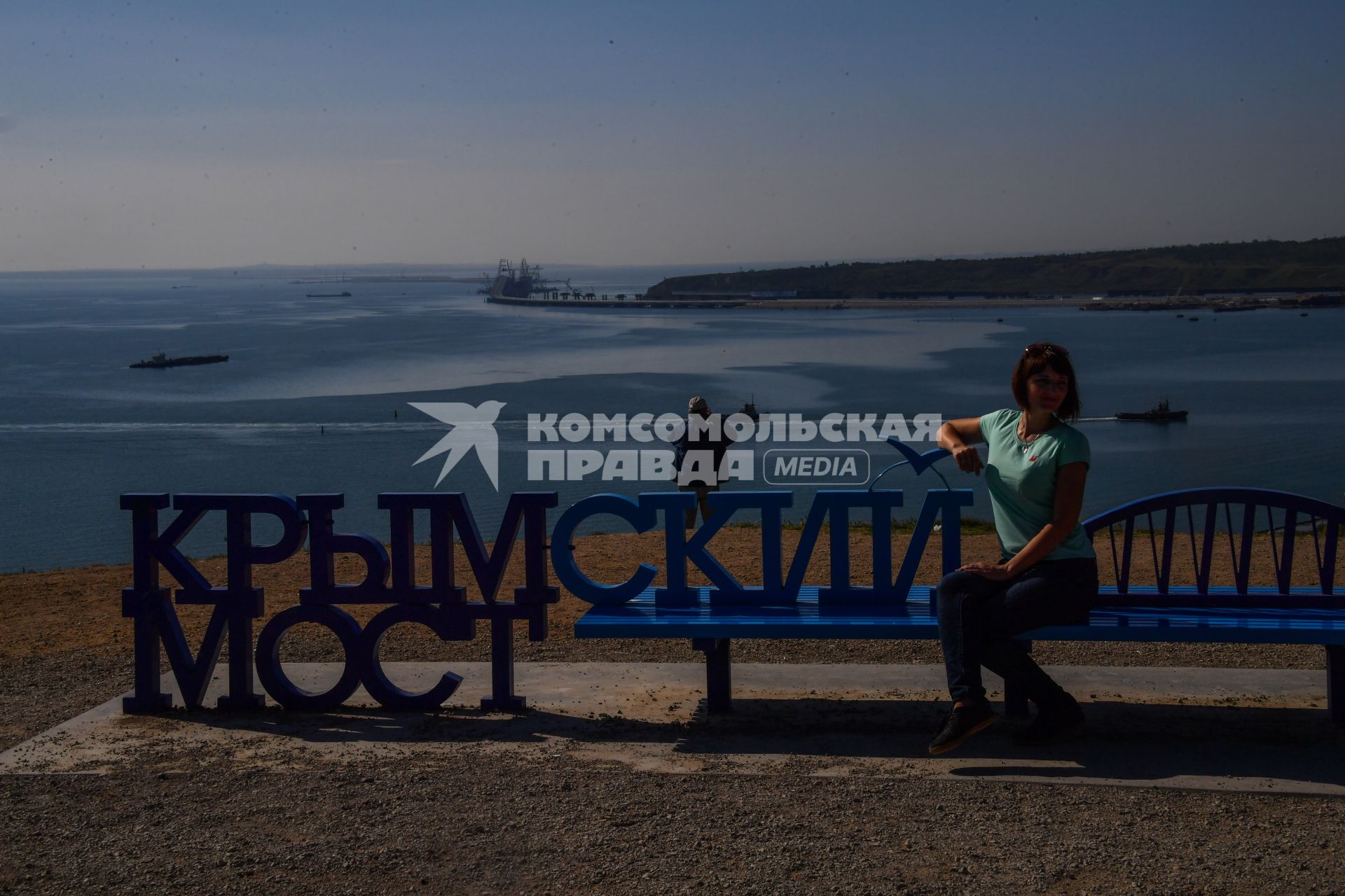 Республика Крым, Керчь. Девушка сидит на скамейке с видом на  Крымский мост и Керченский пролив.