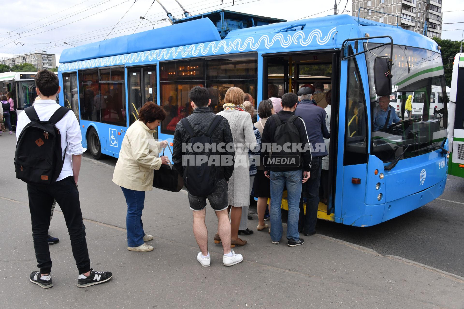 Москва.   Пассажиры садятся в автобус на остановке общественного транспорта.