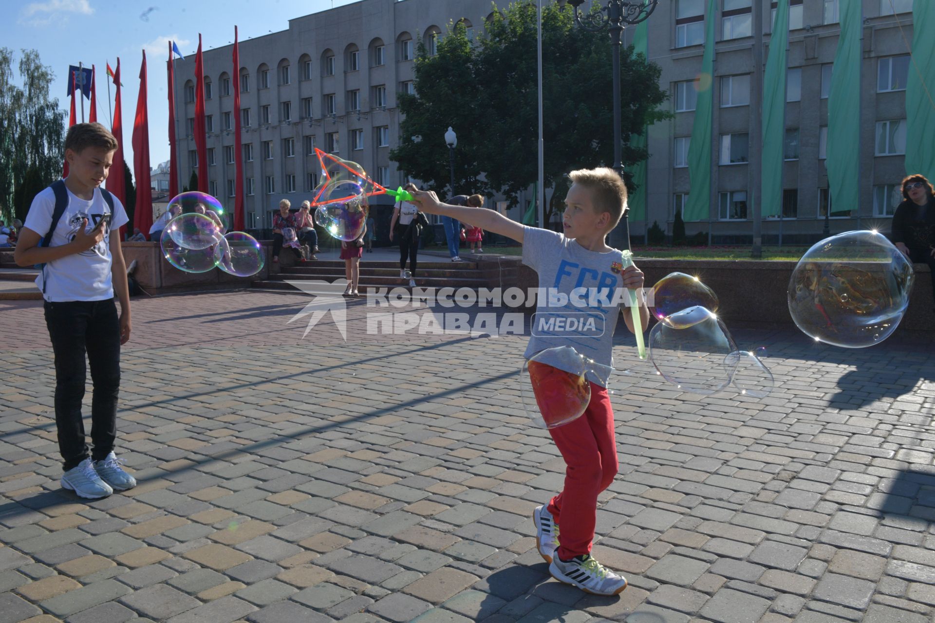 Беларусь, Гродно. Мальчики пускают мыльные пузыри на улице города.