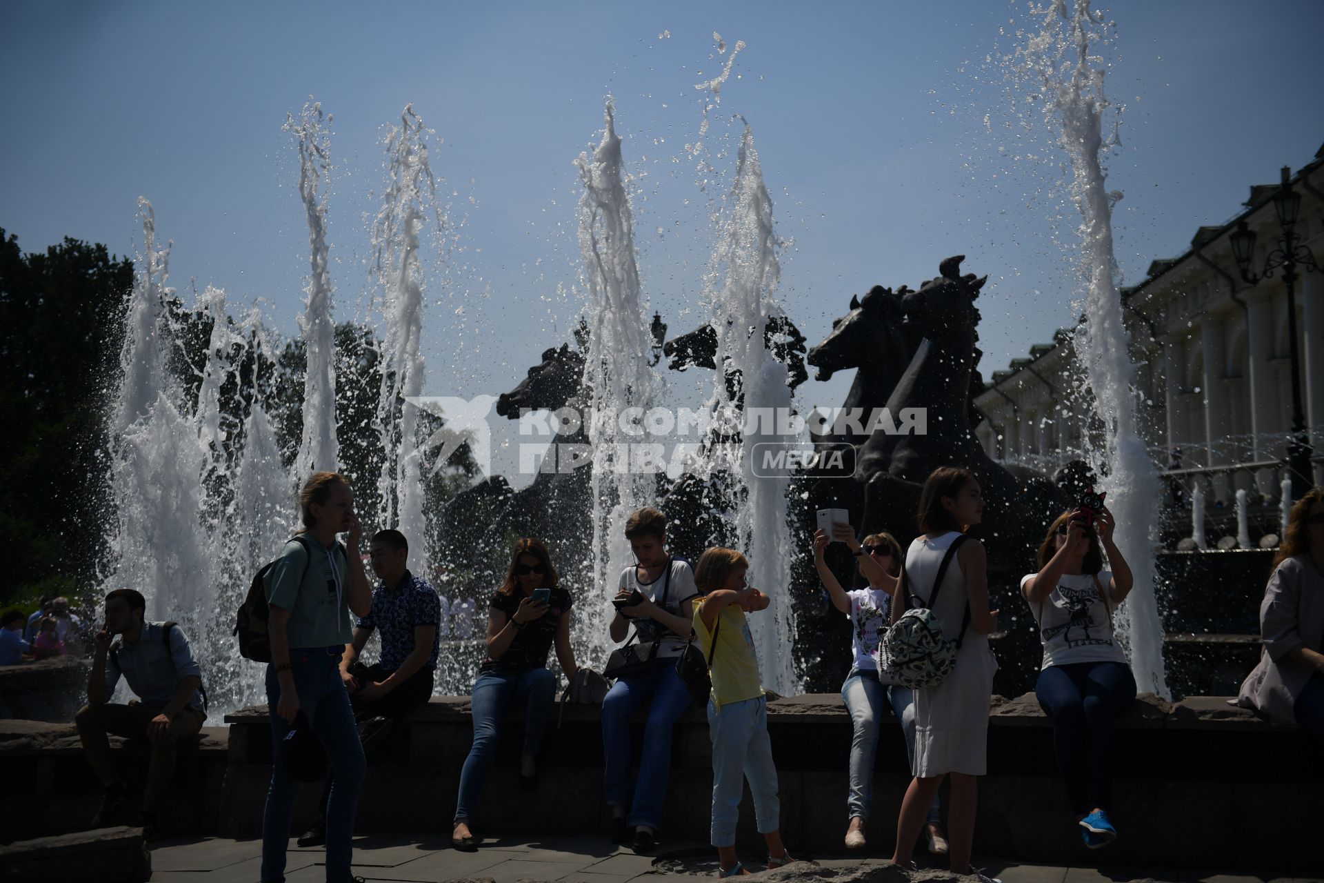 Москва.    Горожане у фонтана `Гейзер` со скульптурой `Времена года` на Манежной площади.