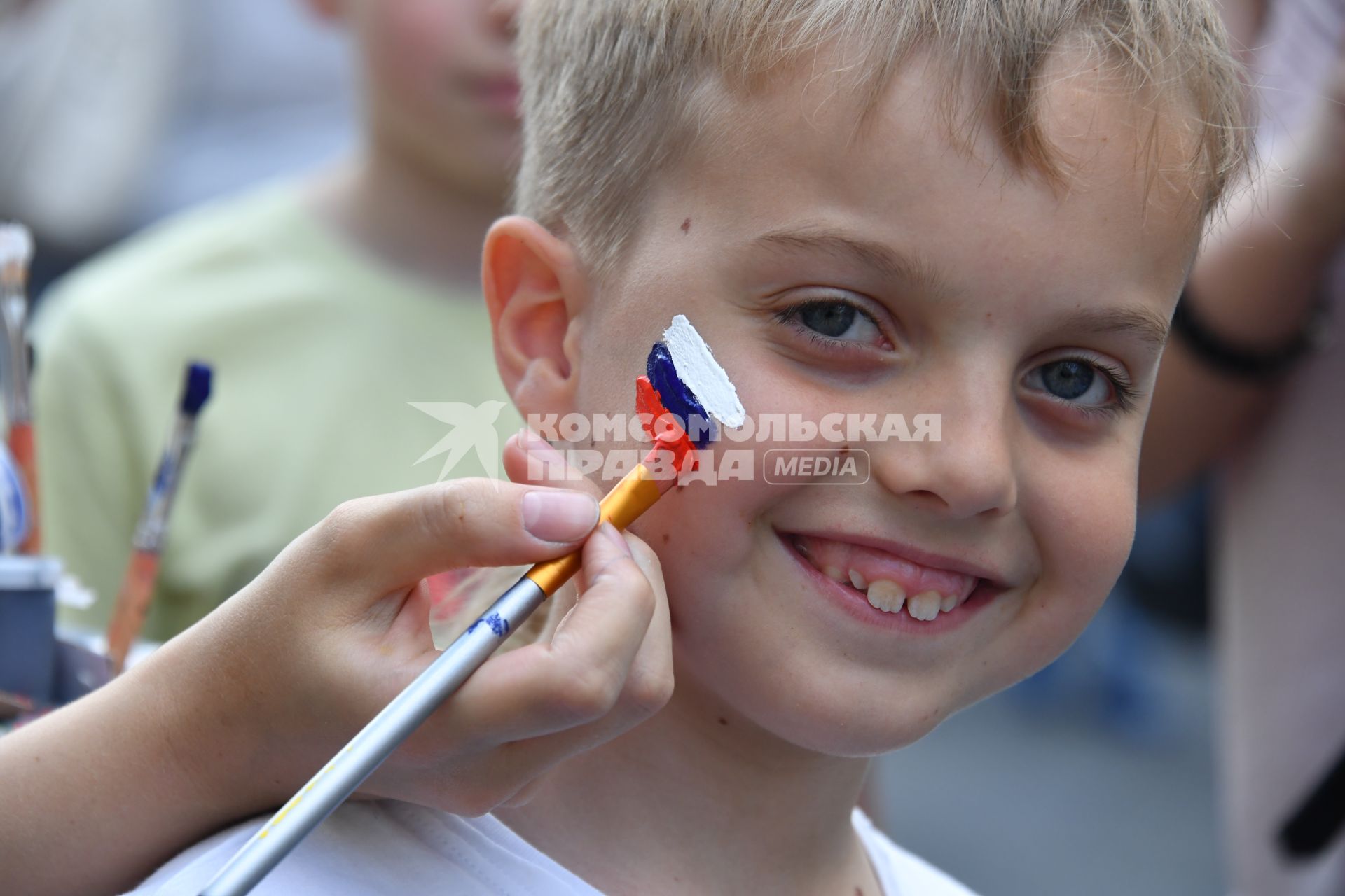 Москва. Мальчику рисуют российский флаг на щеке.