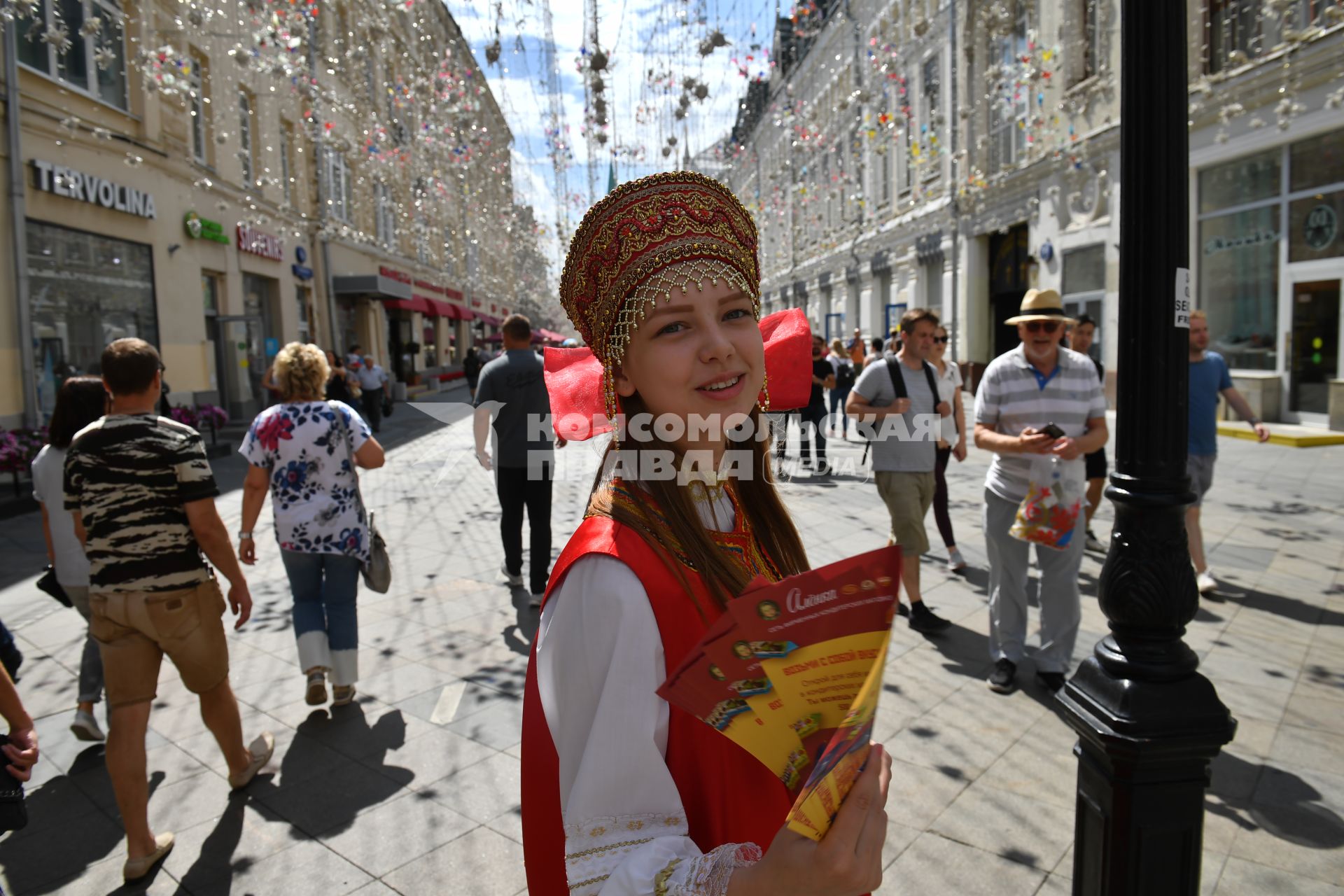 Москва. Девушка в народном костюме раздает рекламные листовки на Никольской улице.