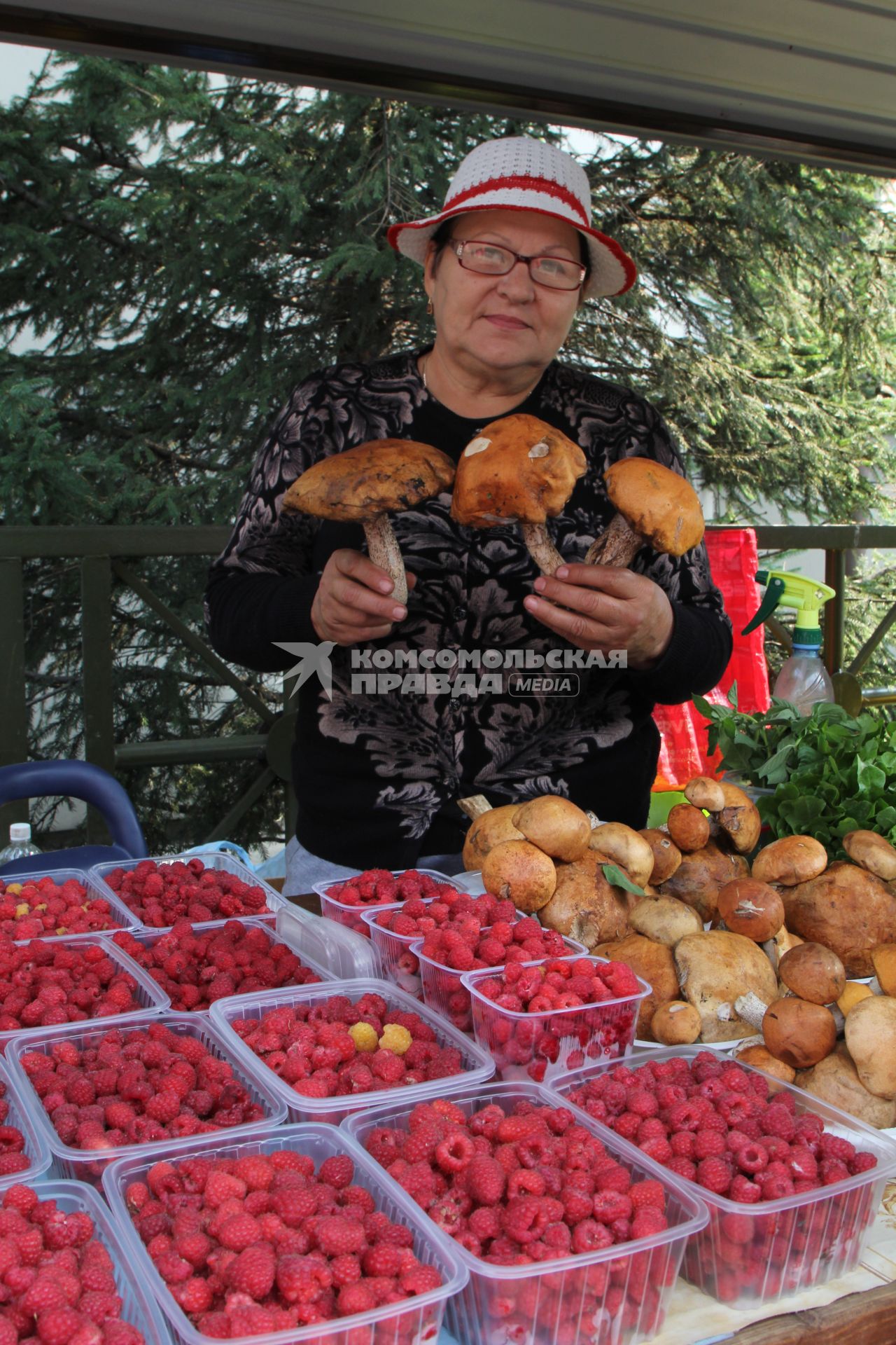 Иркутск.  Женщина продает малину и грибы на рынке.