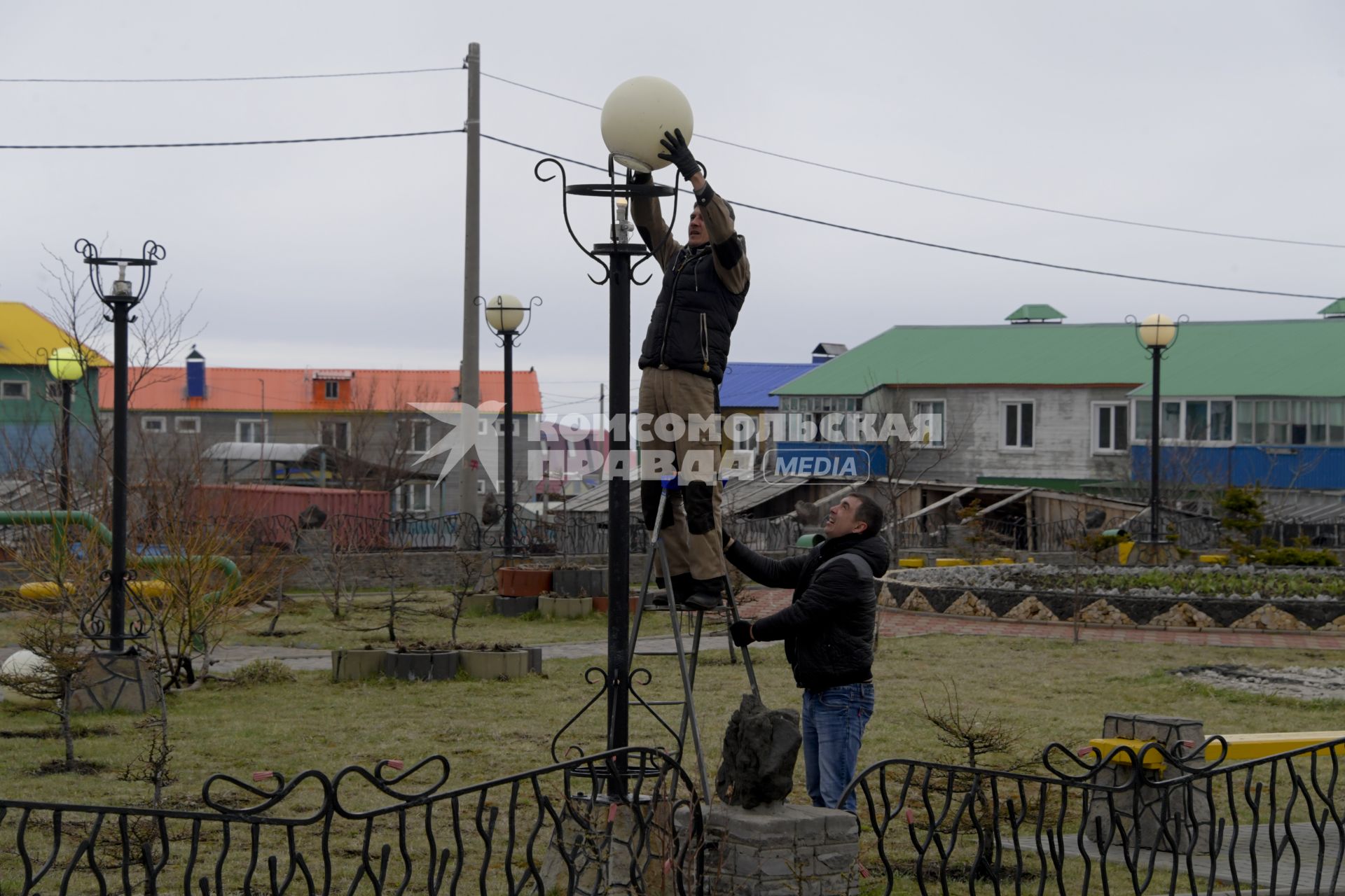 Остров Итуруп, Курильск. Рабочие меняют плафоны на фонарях в городском сквере.