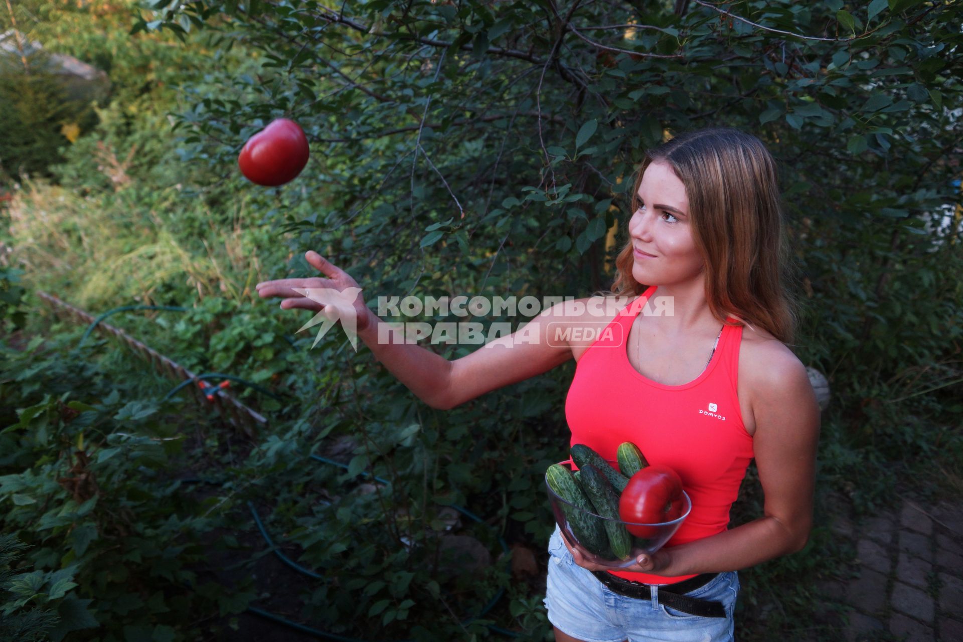Самарская область.  Девушка держит в руках тарелку с огурцами и помидорами.