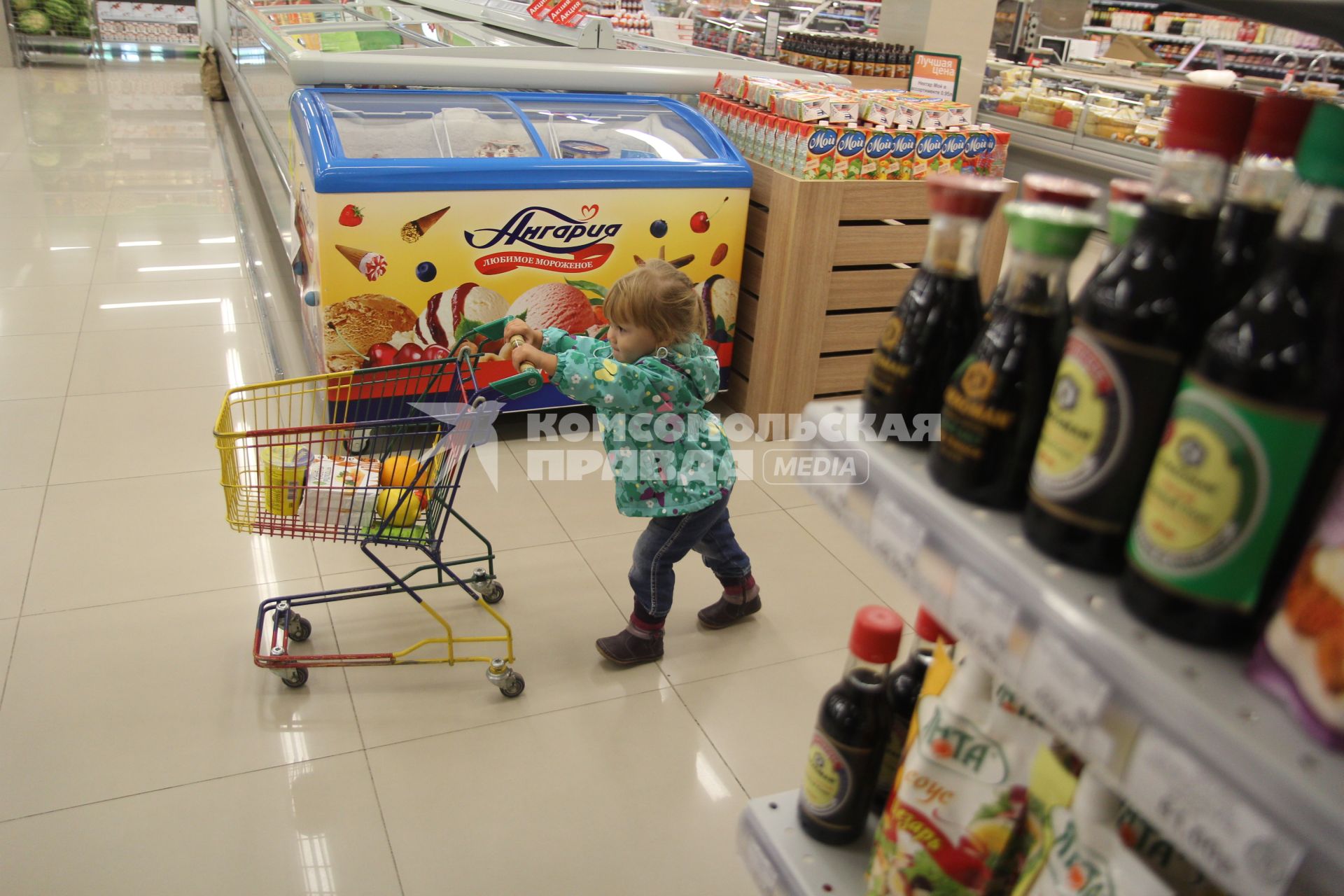 Иркутск.  Девочка с продуктовой тележкой в супермаркете.