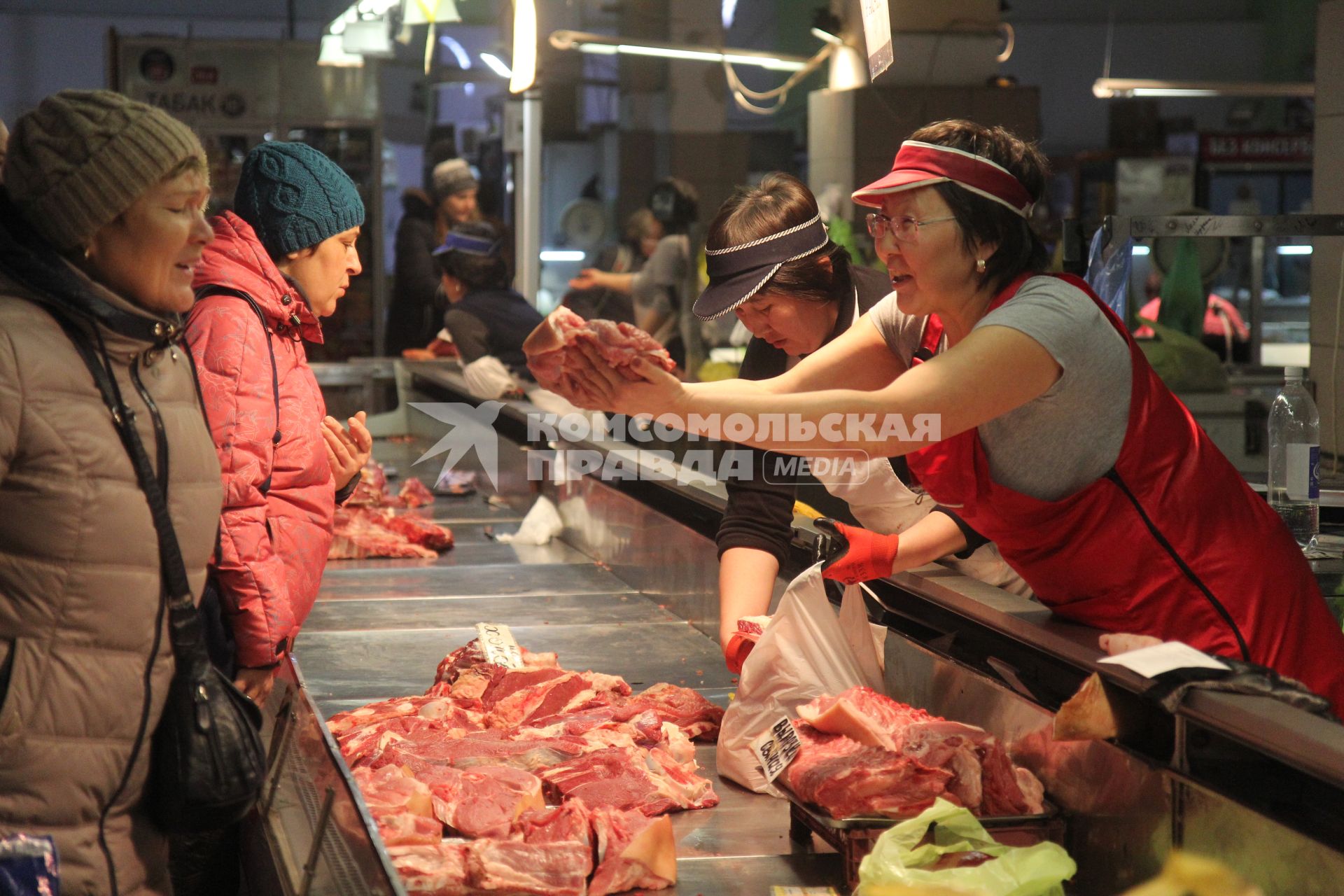 Иркутск. Женщина выбирает мясо на рынке.