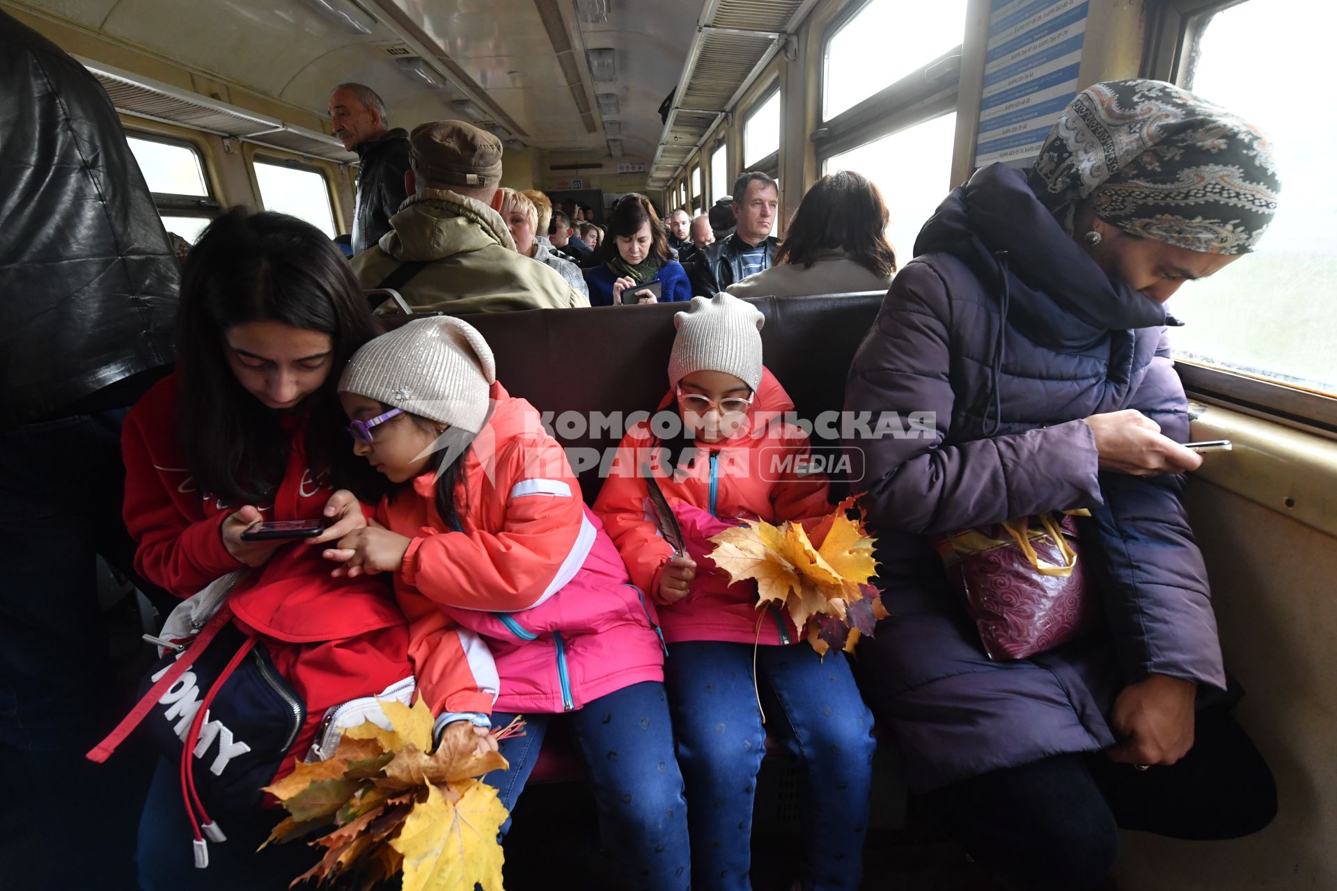 Москва.  Девочки с осенними листьями в электричке.