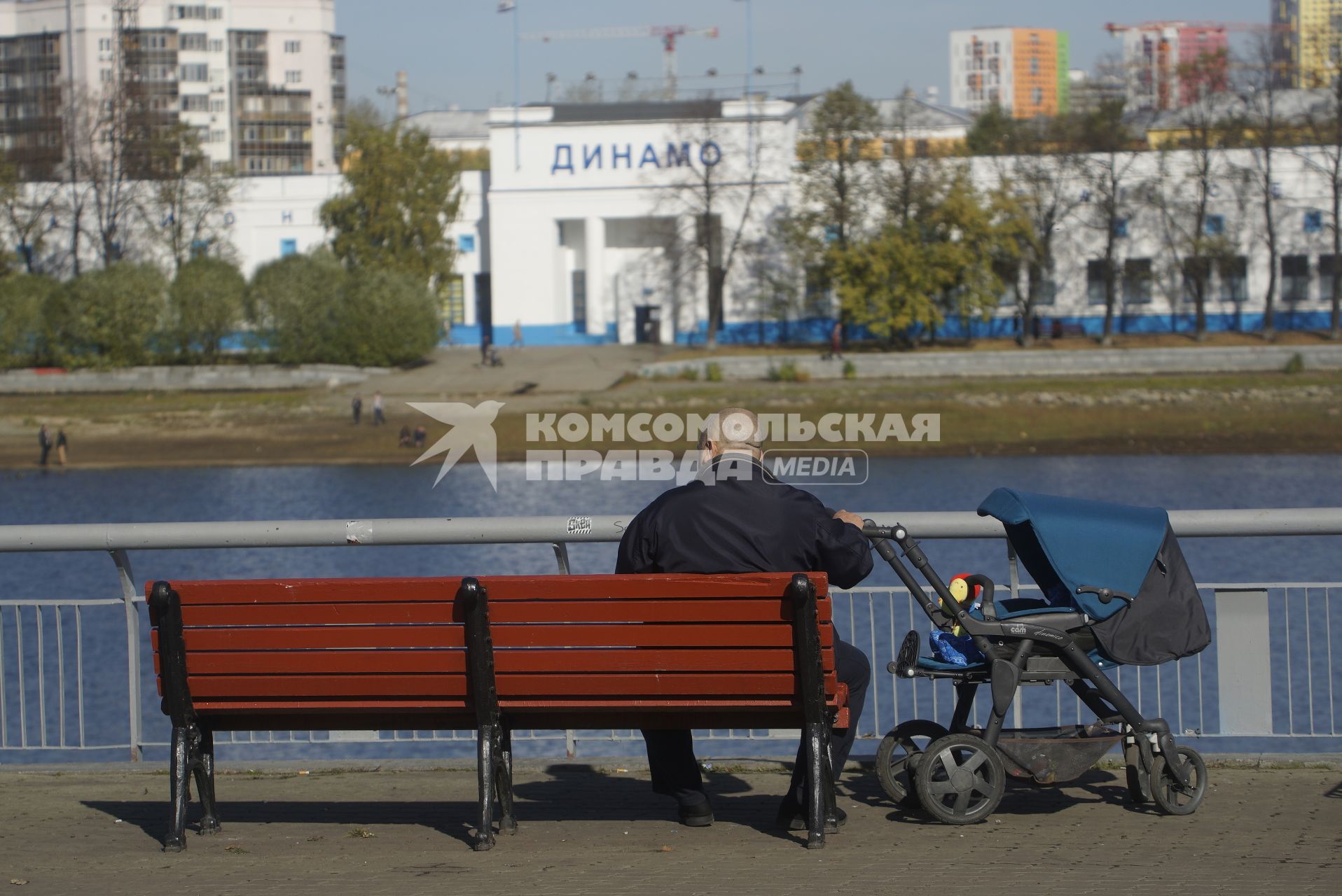 Екатеринбург. Мужчина с детской коляской сидит скамейке на набережной реки Исеть