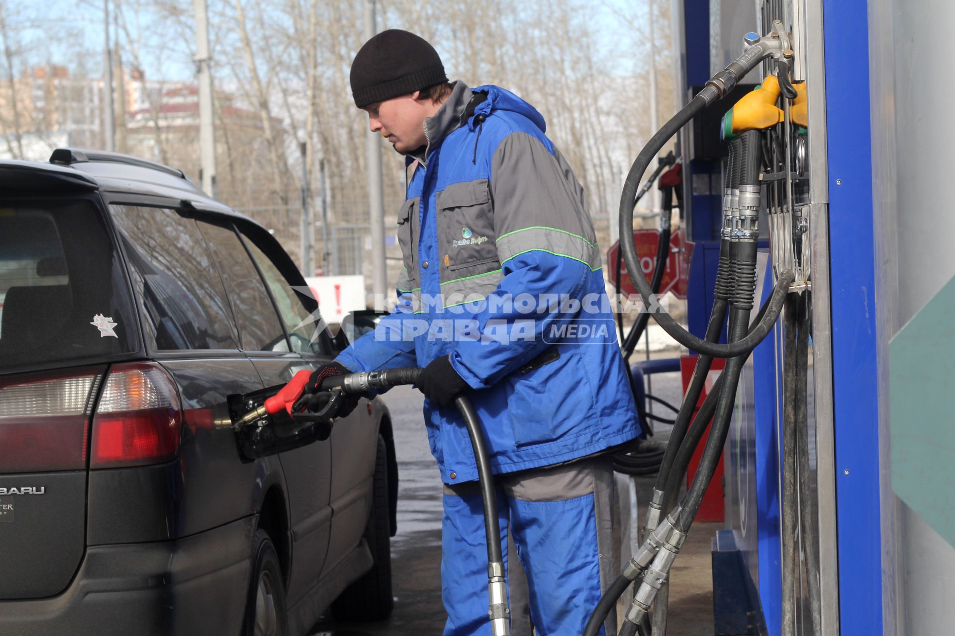 Иркутск.   Сотрудник автозаправочной станции заправляет автомобиль.