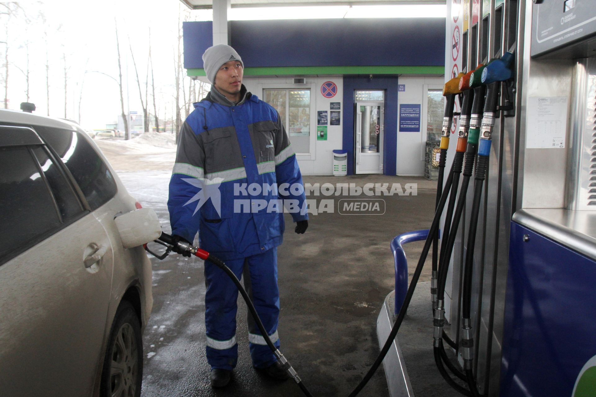 Иркутск.   Сотрудник автозаправочной станции заправляет автомобиль.