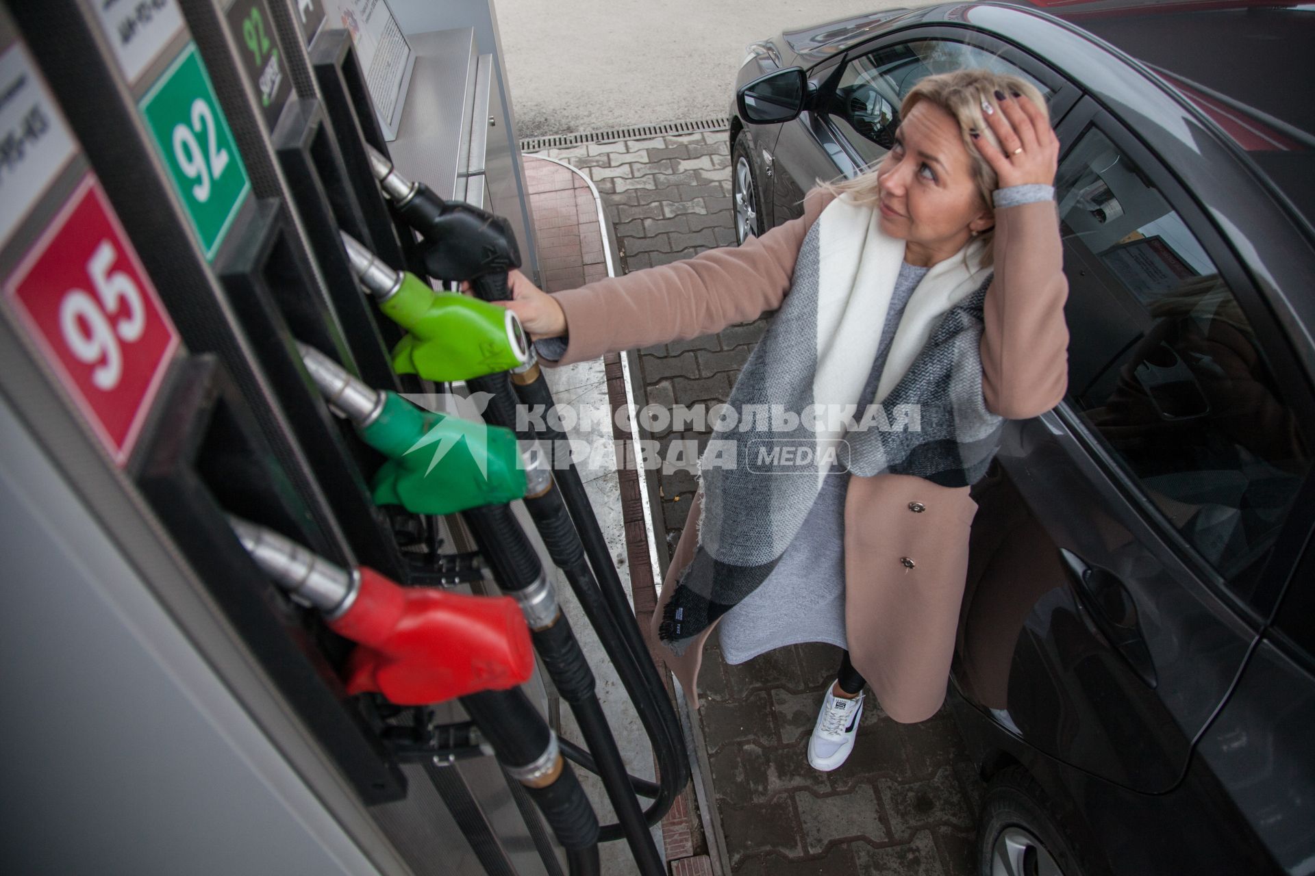 Пермь. Женщина заправляет автомобиль на автозаправочной станции.