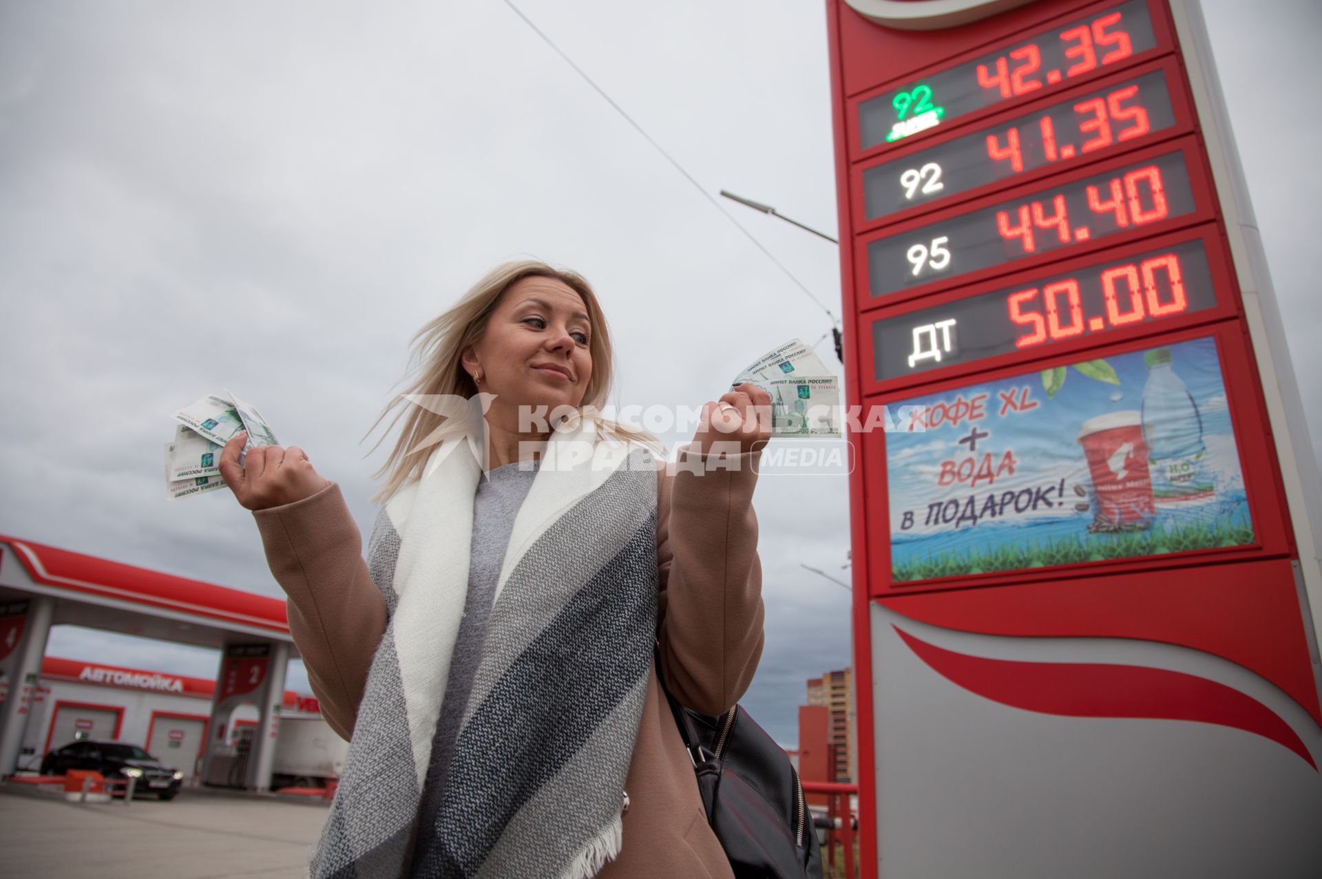 Пермь. Женщина с деньгами в руке на автозаправочной станции.