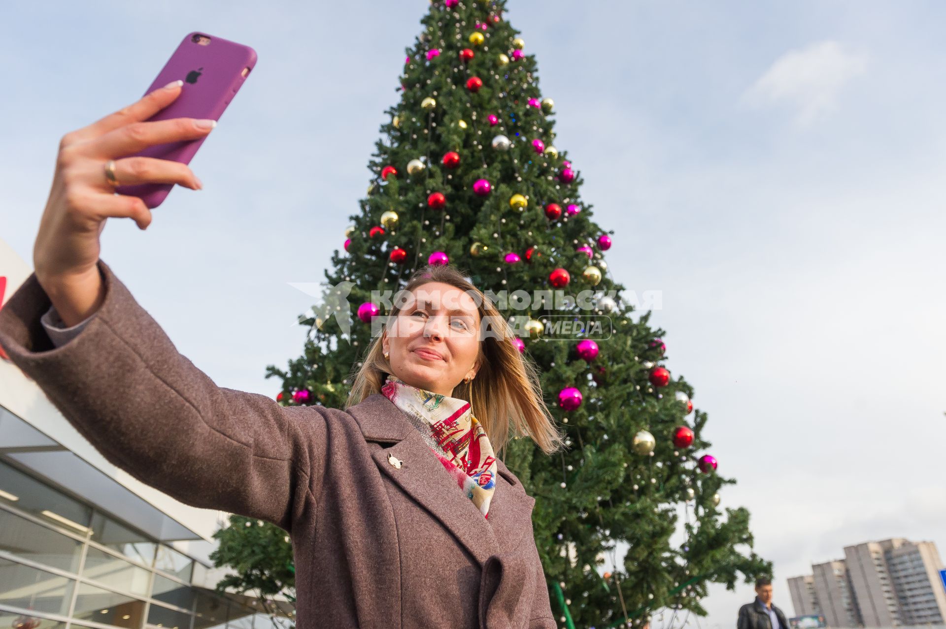 Санкт-Петербург. Девушка делает селфи на фоне новогодней елки на проспекте Маршала Жукова.
