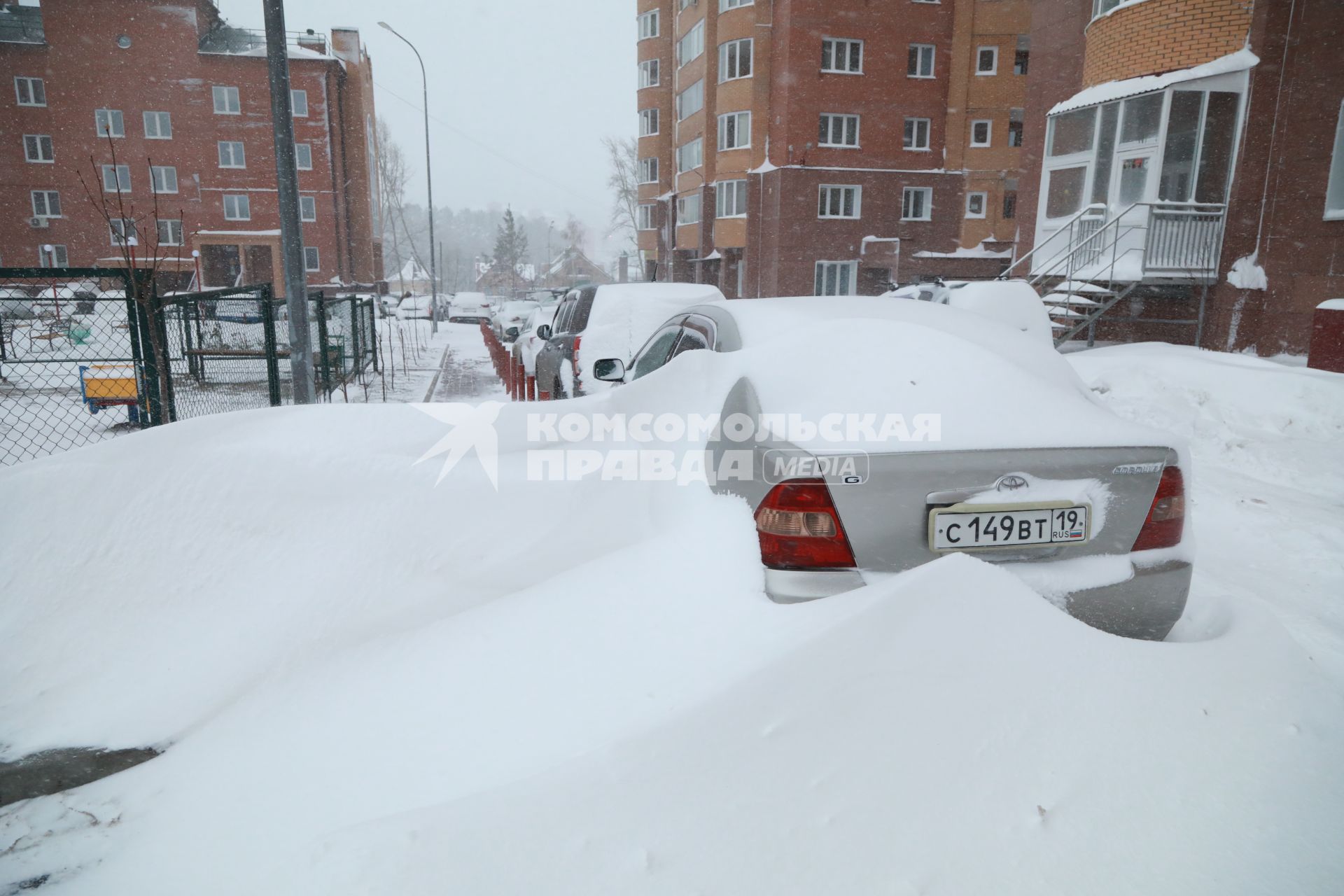 Красноярск.  Занесенные снегом машины на стоянке во дворе дома.