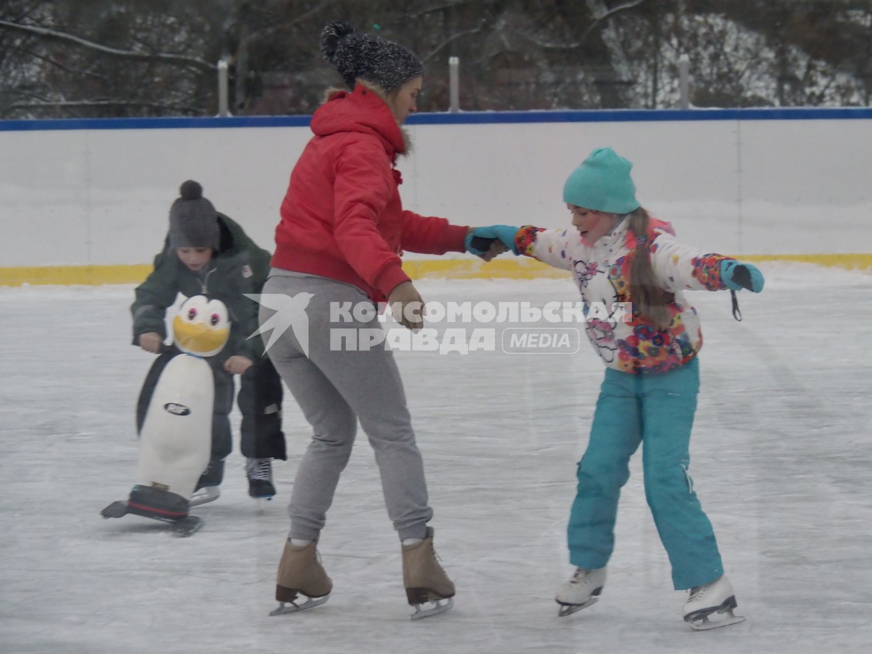 Москва.  Женщина учит девочку кататься на коньках.