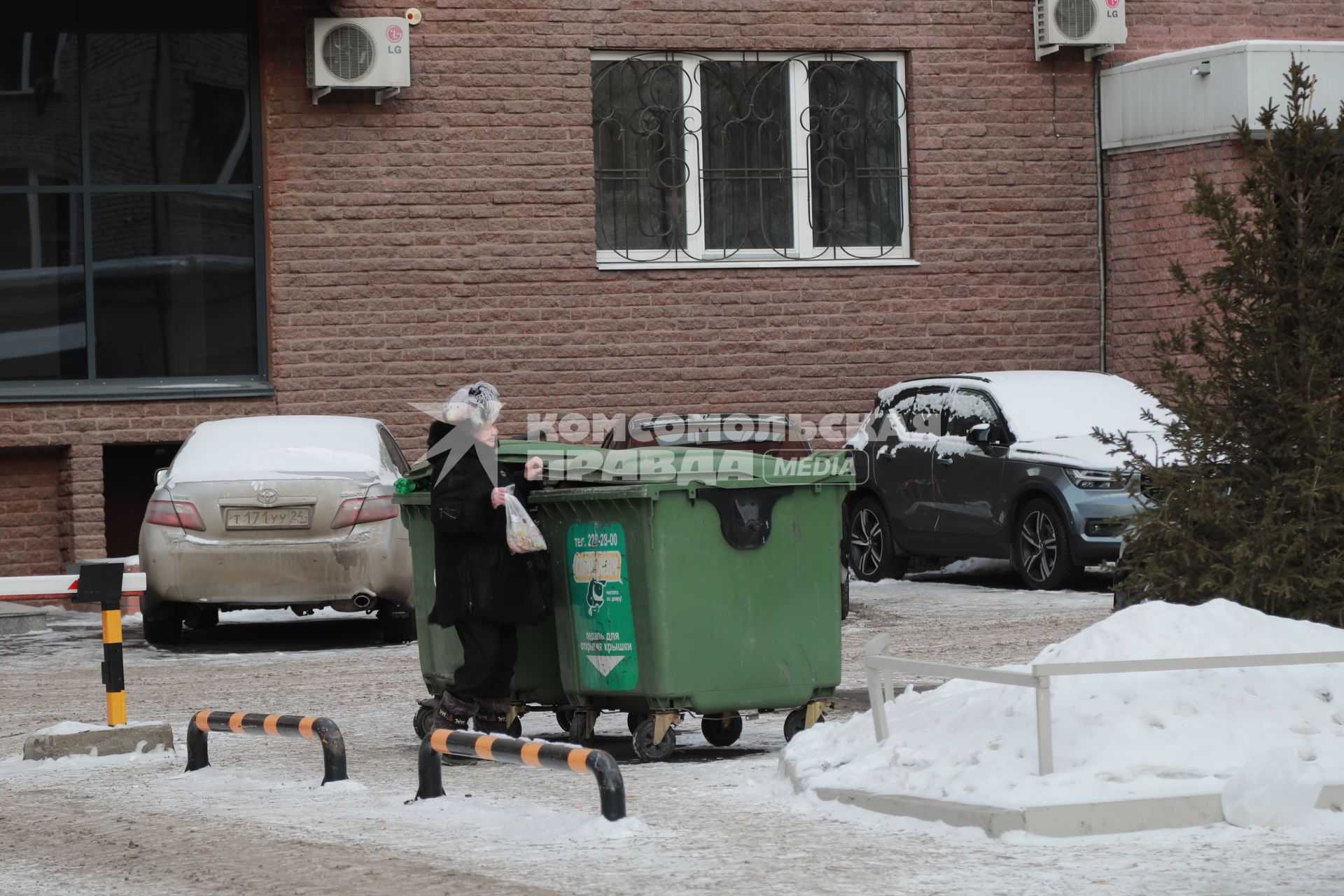 Красноярск.   Женщина выбрасывает мусор в мусорный контейнер.
