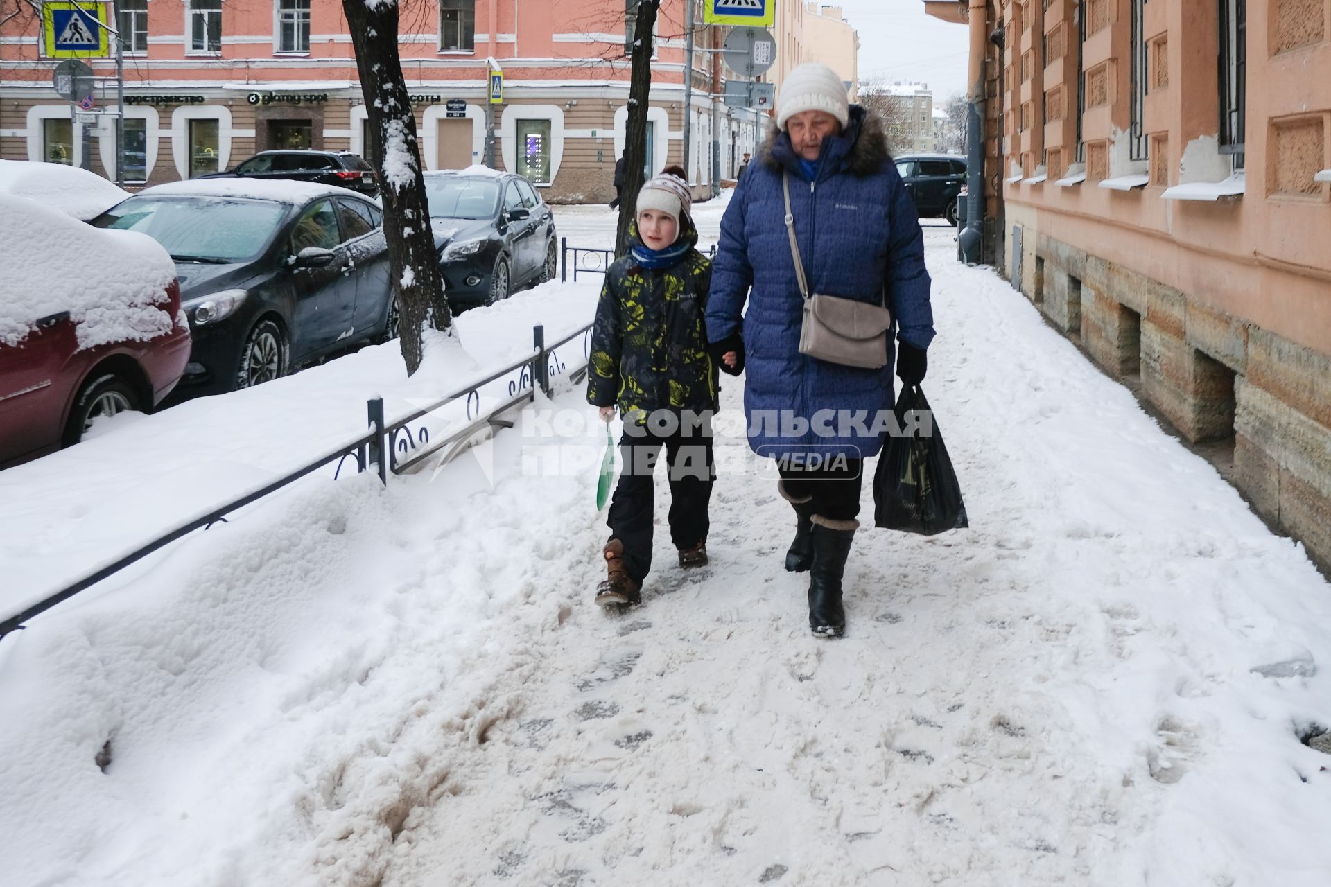 Санкт-Петербург. Женщина с ребенком идет по неубранной от снега улице.
