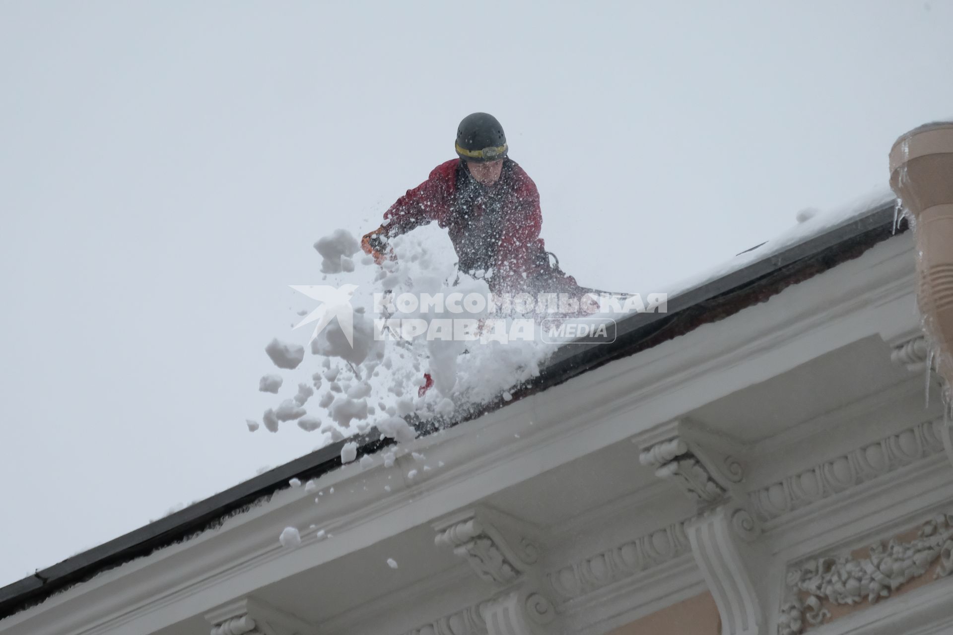 Санкт-Петербург. Сотрудник коммунальных служб счищает снег с крыши дома.
