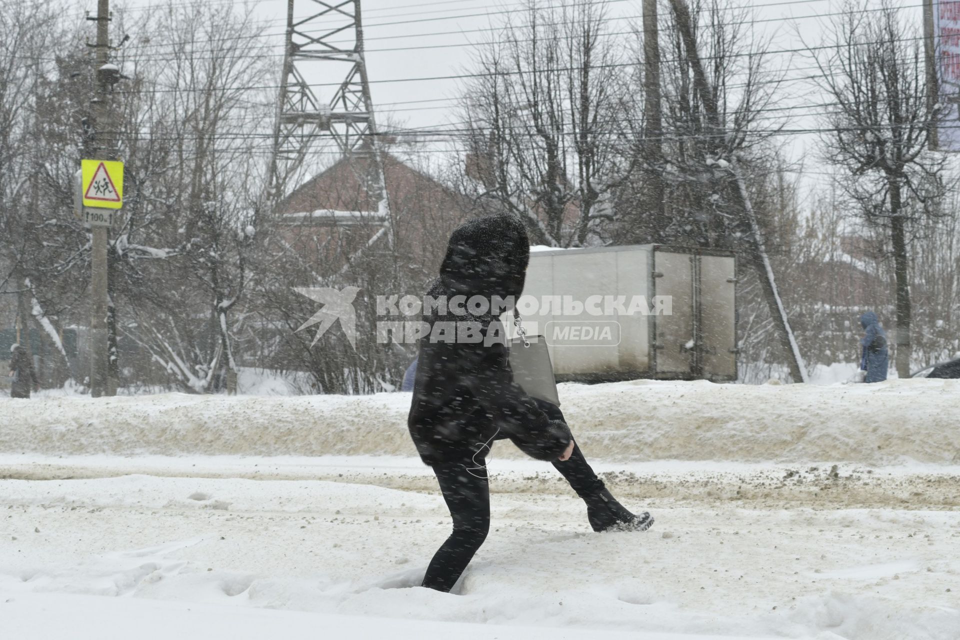 Тула. Девушка перелезает через сугроб на одной из улиц города.