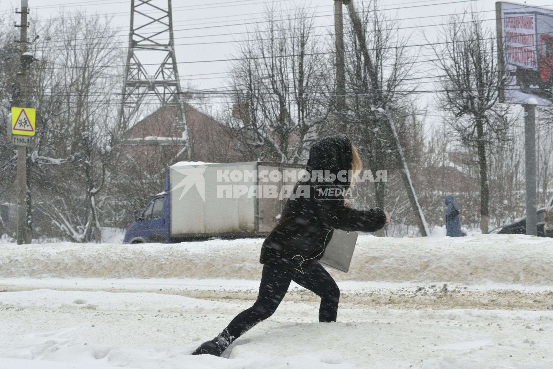 Тула. Девушка перелезает через сугроб на одной из улиц города.