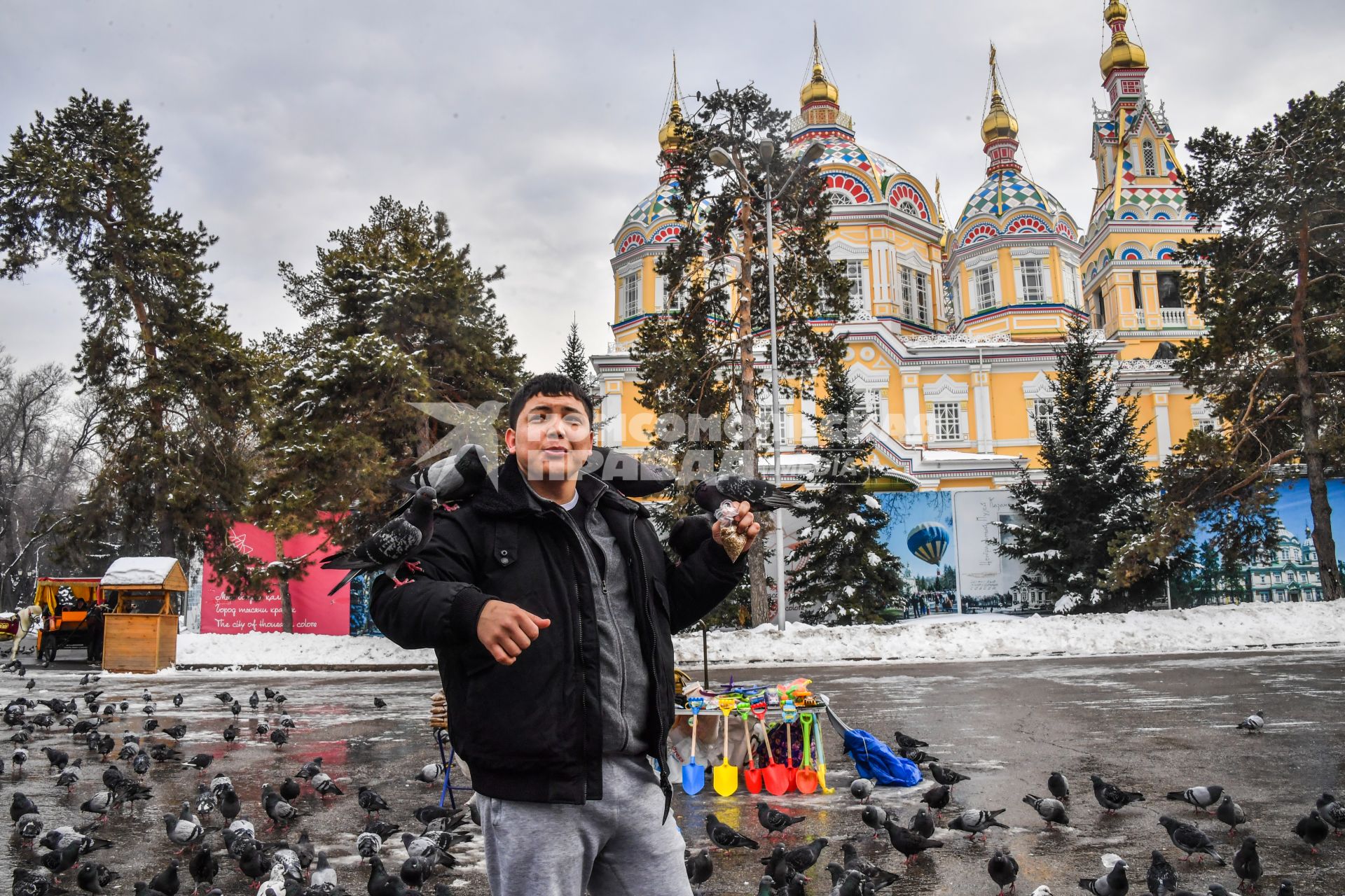 Казахстан, Алма-Ата. Мужчина кормит голубей у Вознесенского собора Астанайской и Алматинской епархии Русской православной церкви на территории парка имени 28 гвардейцев-панфиловцев.