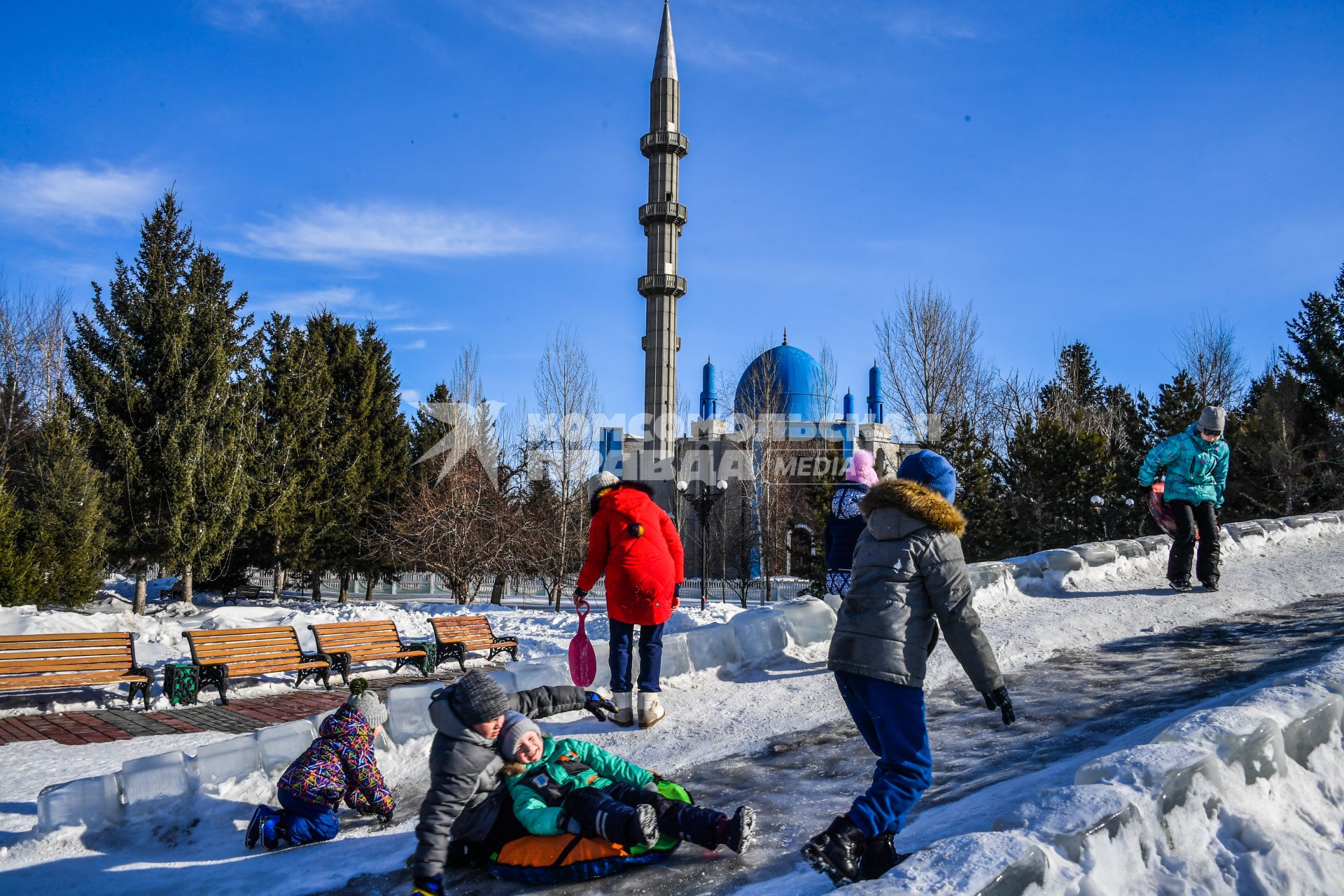 Казахстан, Усть-Каменогорск. Дети катаются с ледяной горки в парке у Мечети  Мухамади.