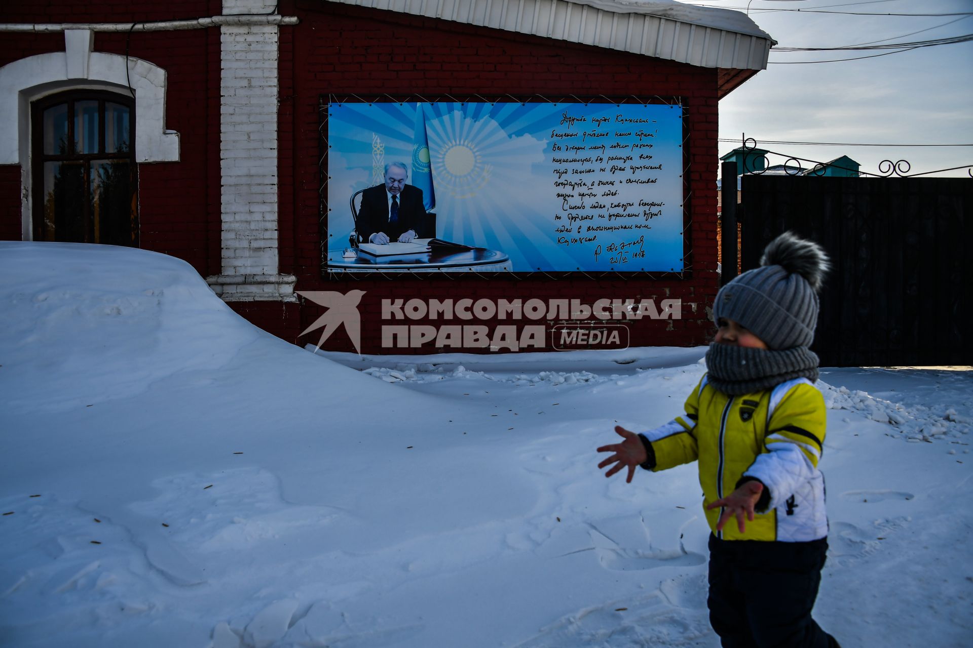 Казахстан, Усть-Каменогорск.  Мальчик у баннера с цитатой  президента Казахстана Нурсултана Назарбаева.