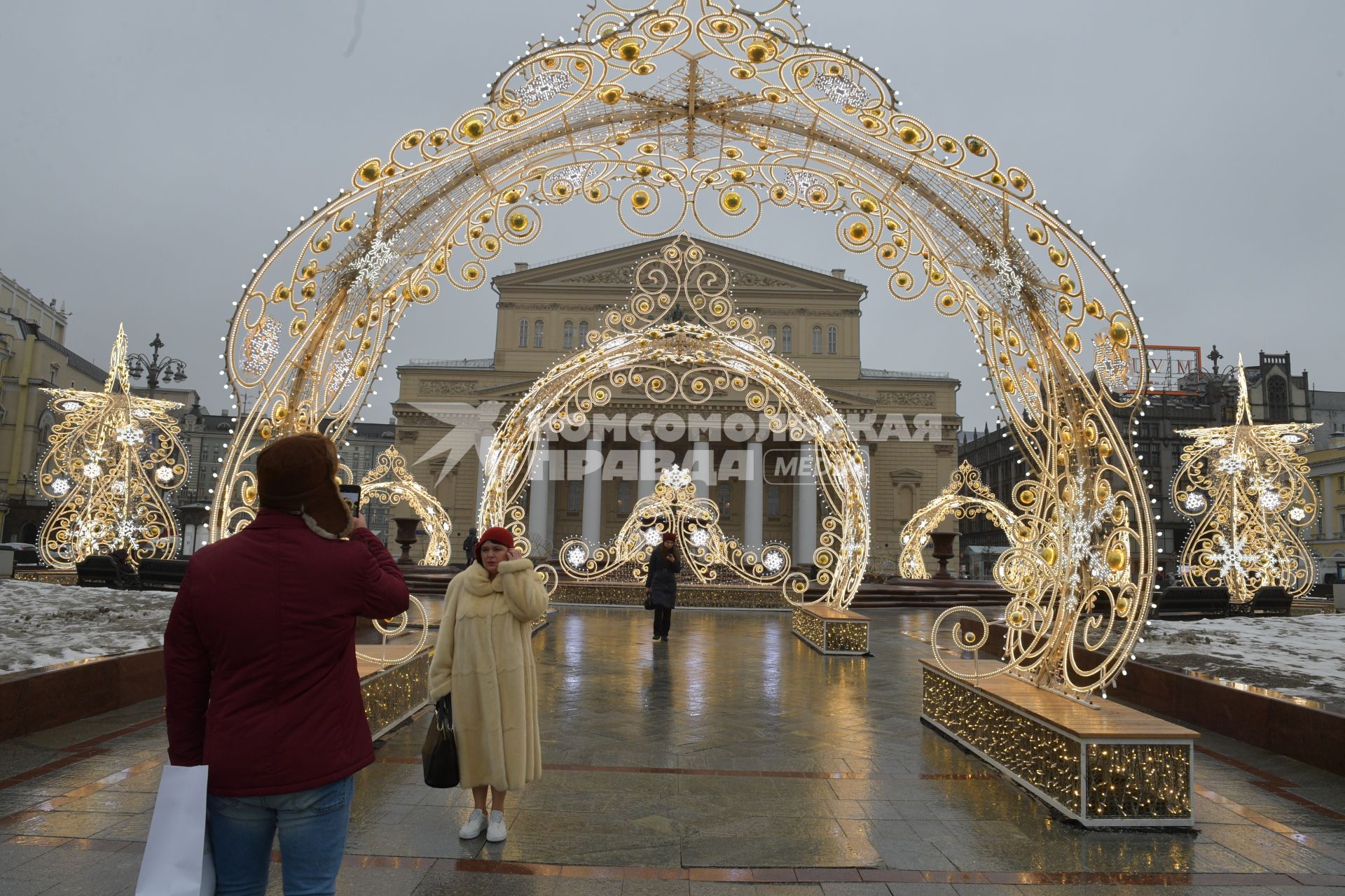 Москва.  Женщина фотографируется на фоне декоративного оформления Театральной площади.